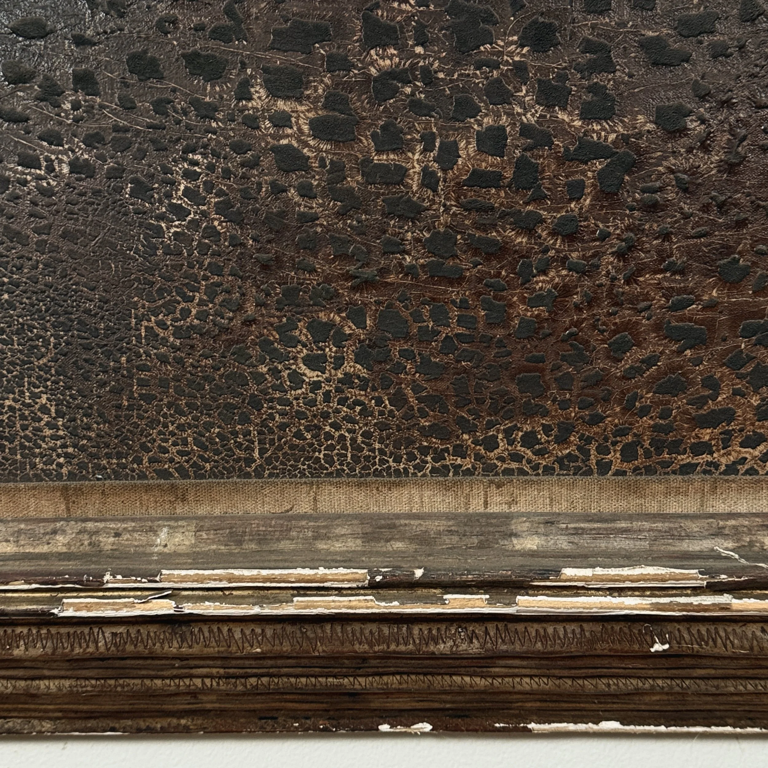 View of the hand-carved wood frame, showing decorative motifs and wear.