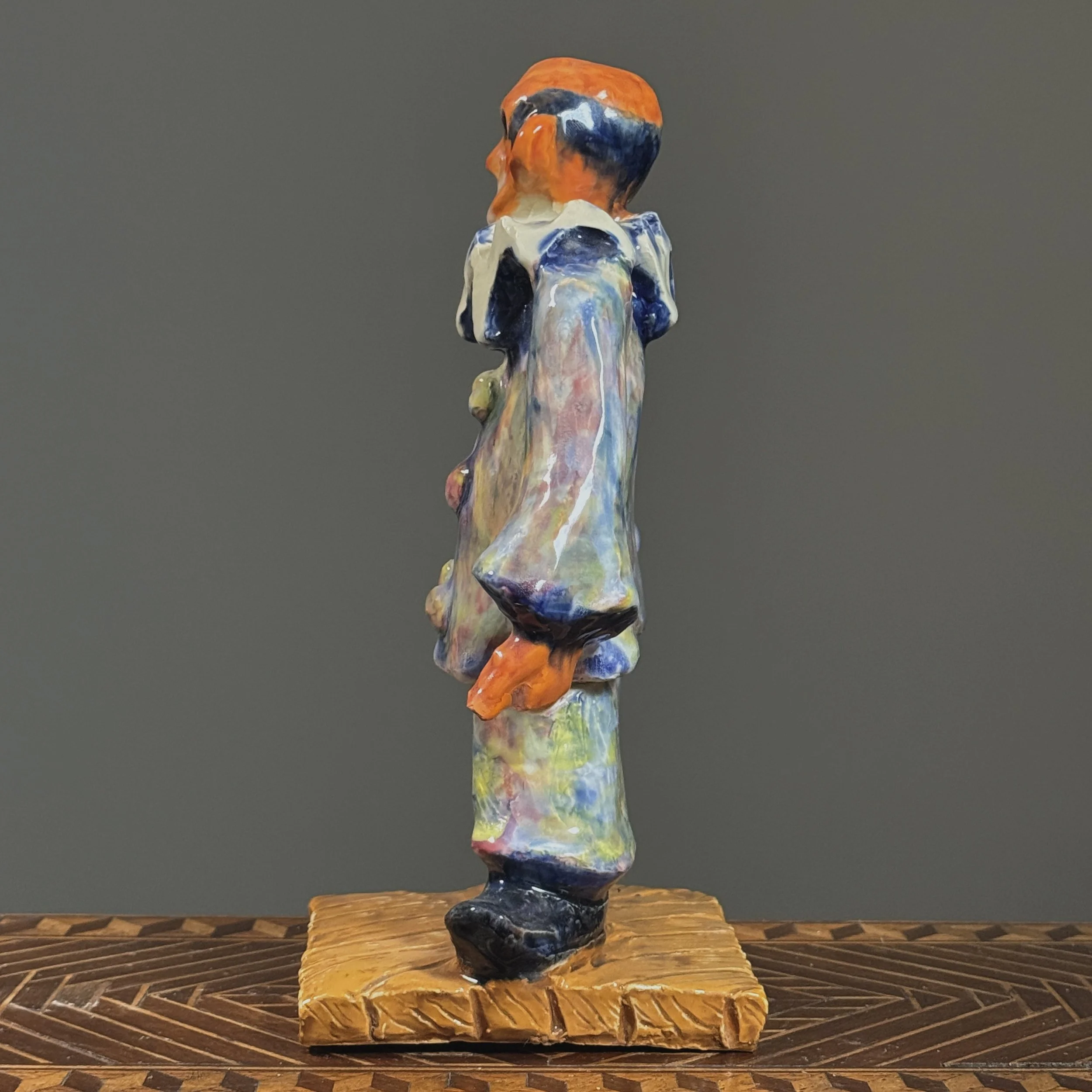Profile view of the expressionist ceramic clown, showing the sculptural form and posture.