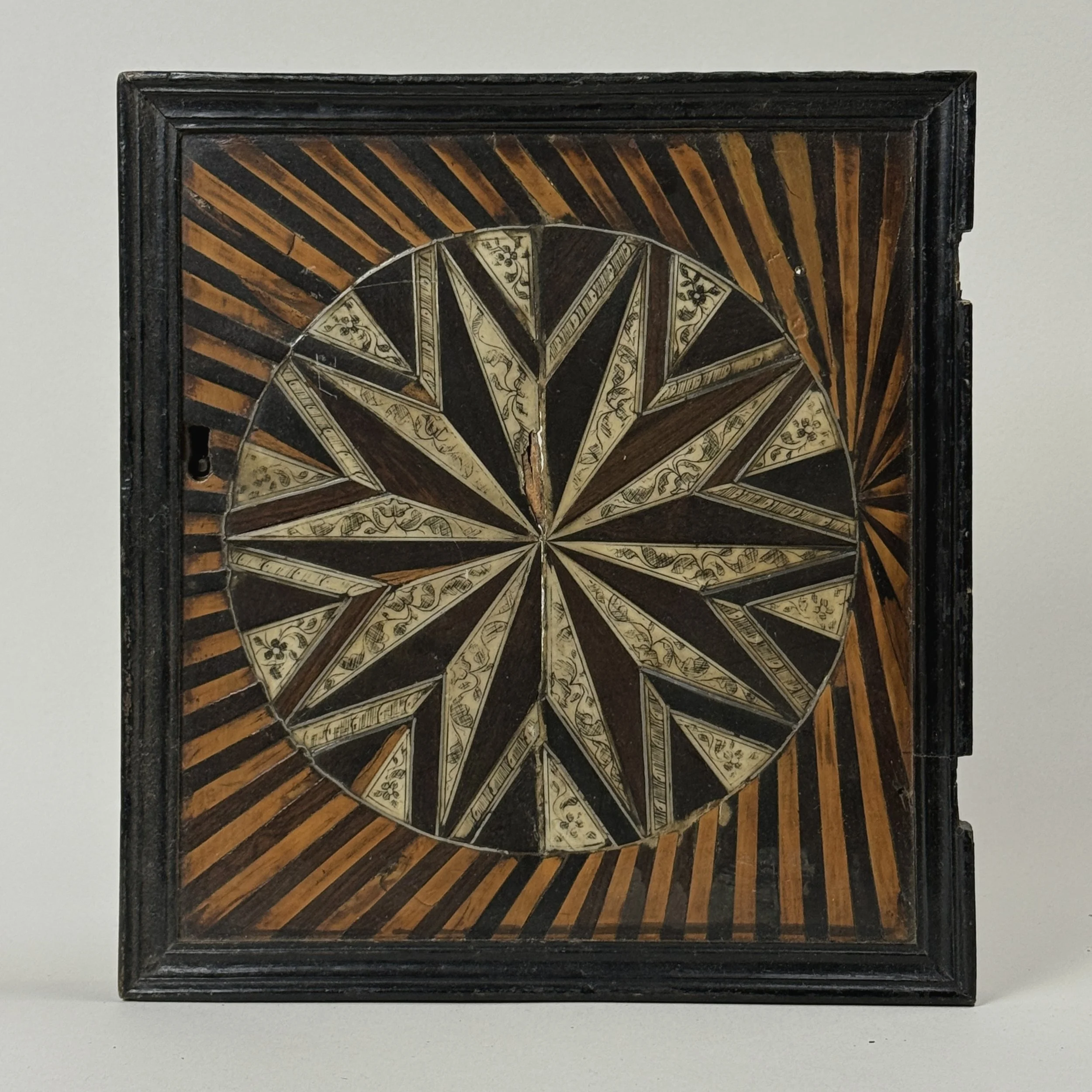 Front view of cabinet doors. Two-tone sunburst parquetry. Hand carved wood.