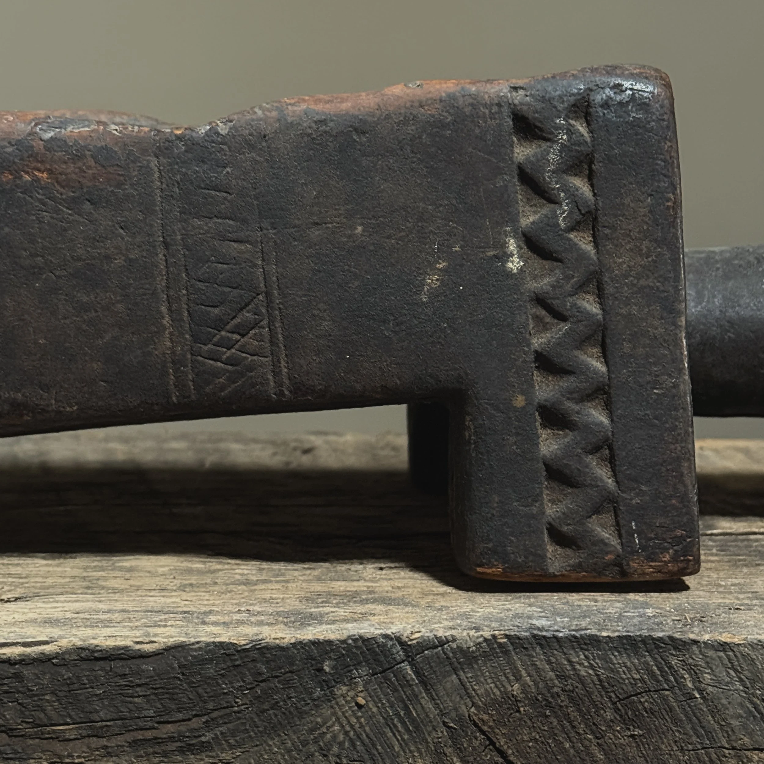Close-up of geometric carving on side of antique African mancala board