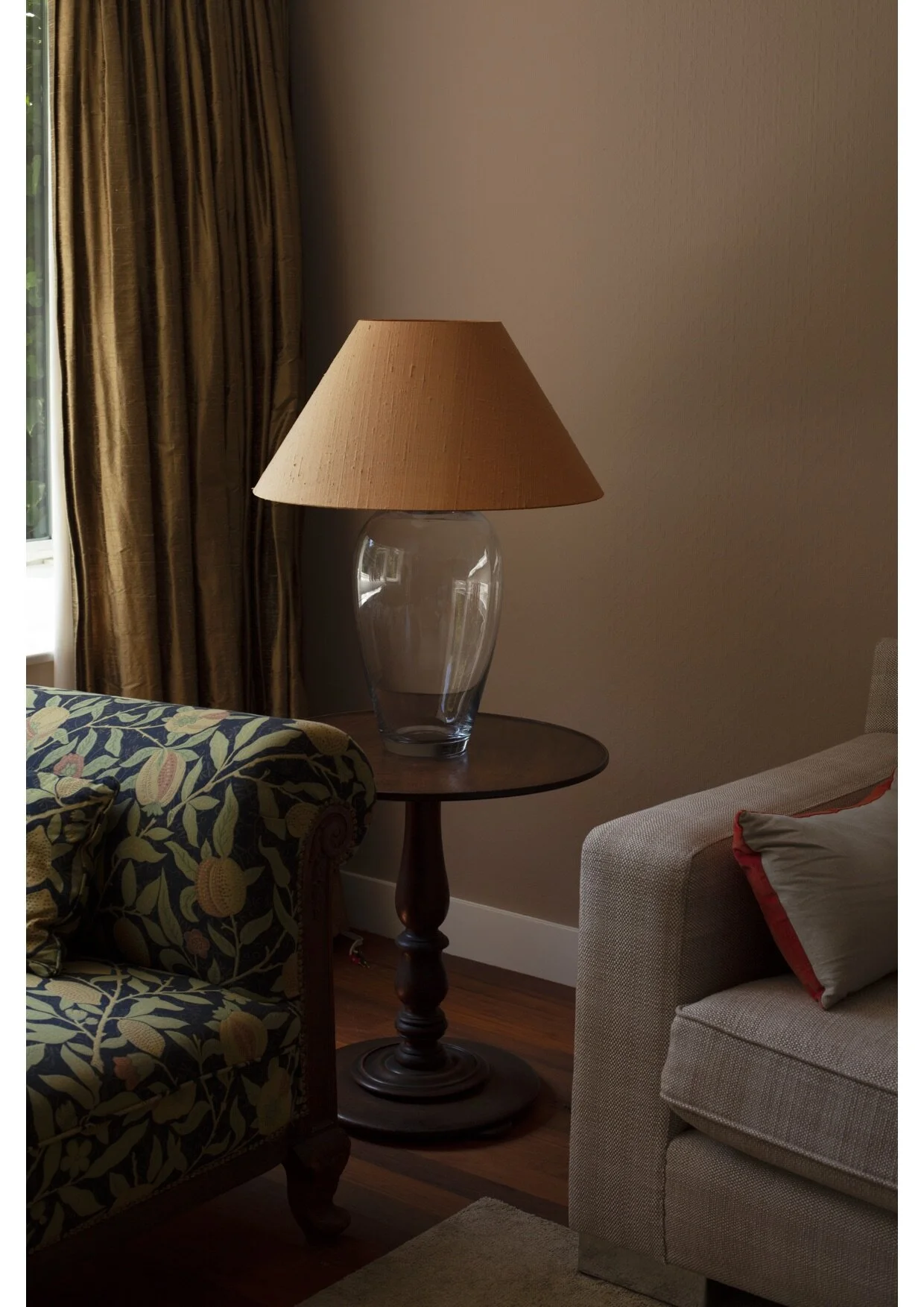 An Empire sofa from 1820 upholstered in William Morris, raw gold silk curtains and a handblown table lamp by Venini on a French 19th c. walnut wooden side table.