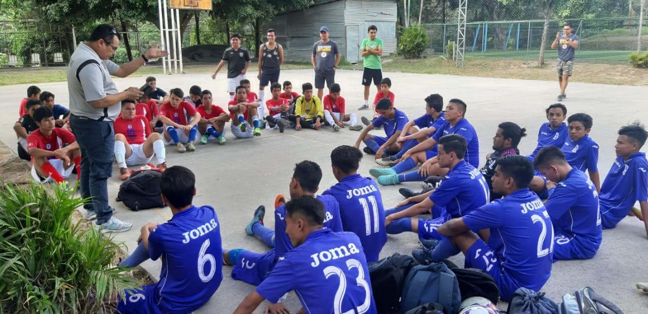 Two soccer teams sit and listen to the Word of God 