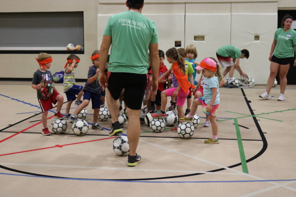 Young kinds practicing soccer skills in a gym