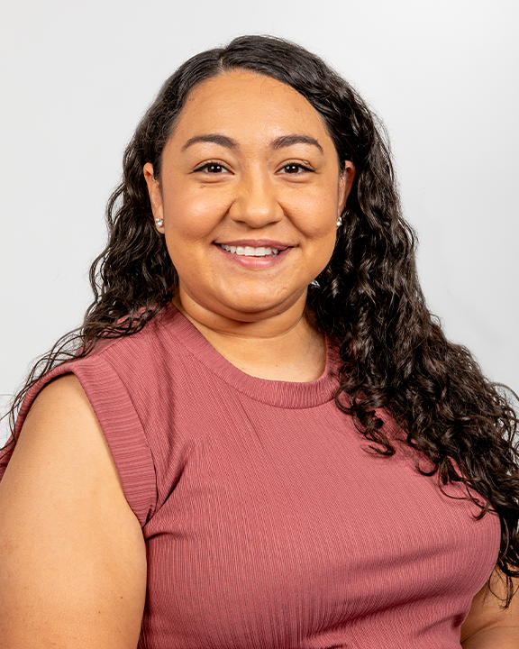 A woman smiling and holding a sign with a white dove on a turquoise background.