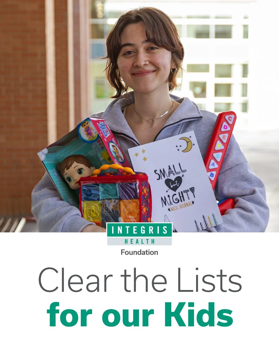 A smiling woman holding various children's toys and a card that reads 'Small but Mighty.'