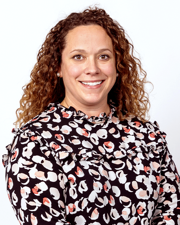 Woman with curly hair, glasses, and a black blazer holding speech bubbles with stickers of lungs and a hand print.