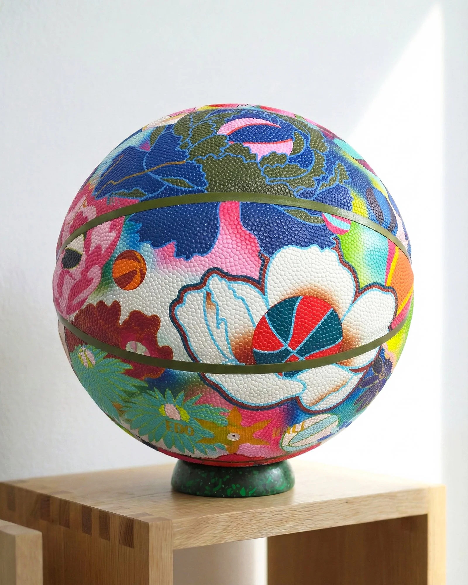 Edo Ball floral art basketball displayed on green terrazzo stand, designer basketball art object with matching display base.