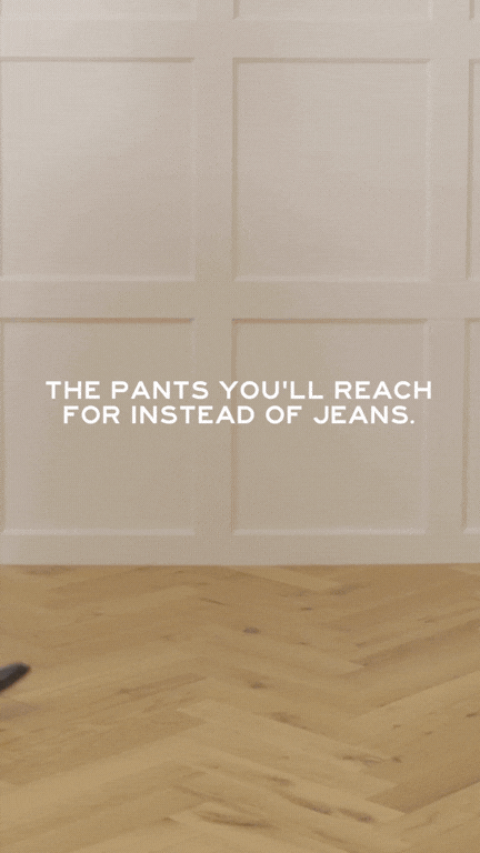 A white garage door with a humorous message in white text that says, 'The pants you'll reach for instead of jeans,' and a wooden floor at the bottom.