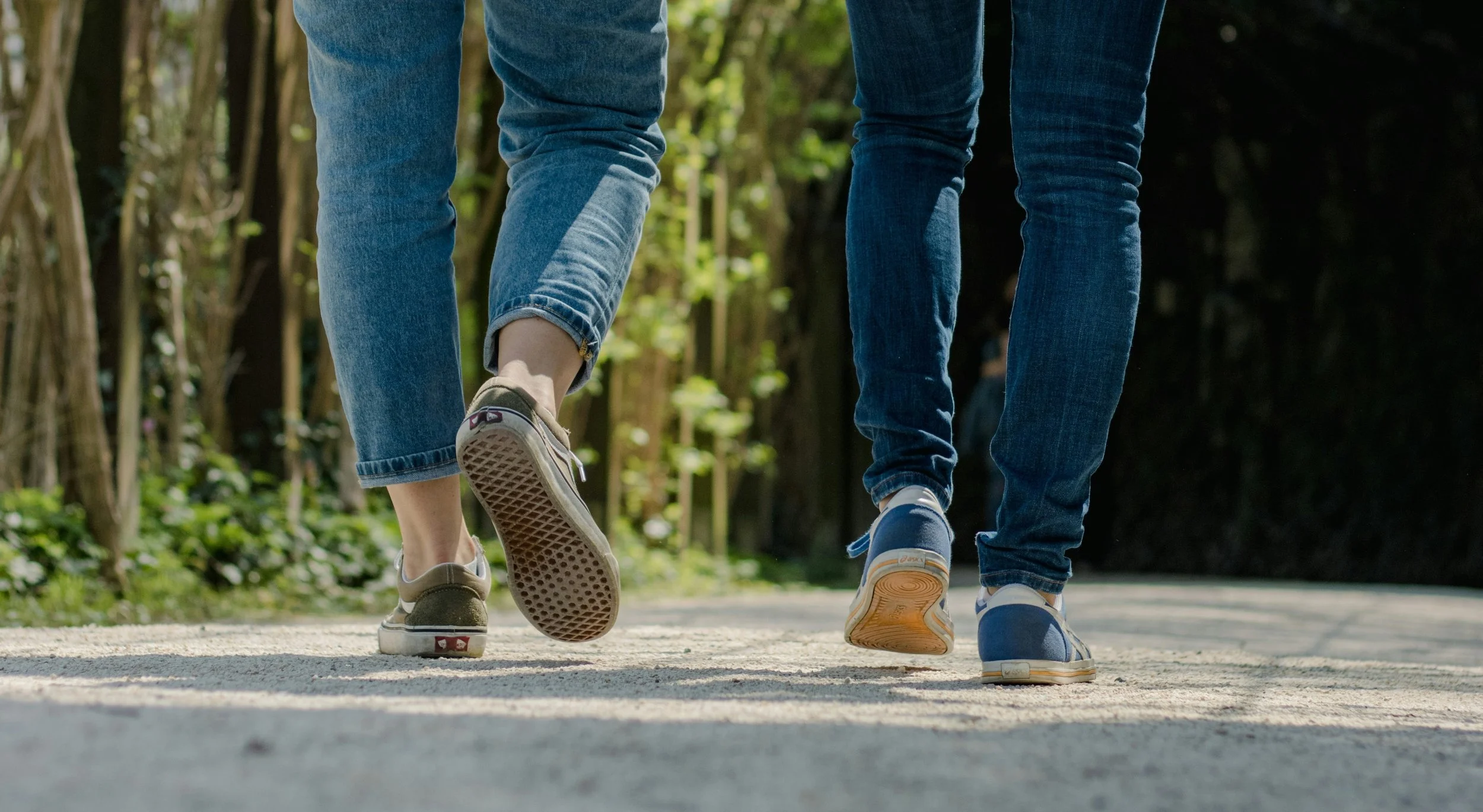 Two people's legs and feet walking on a path