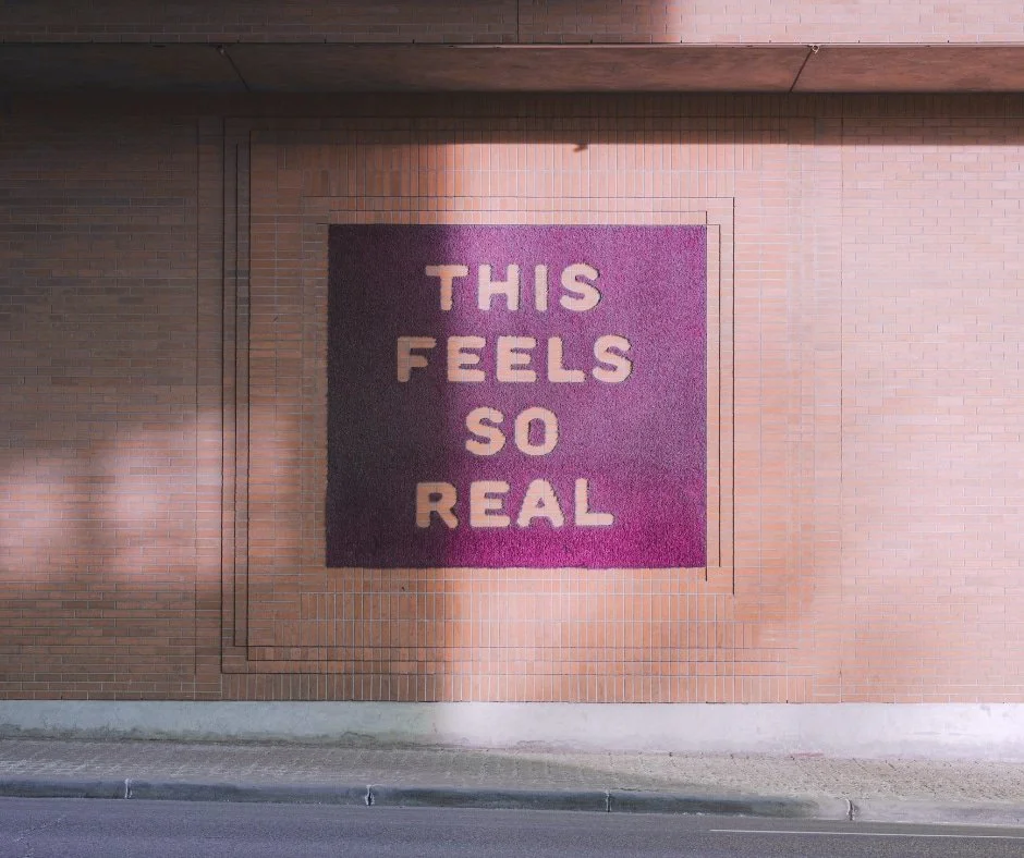 Bricj wall with the words, this feels so real written on them.