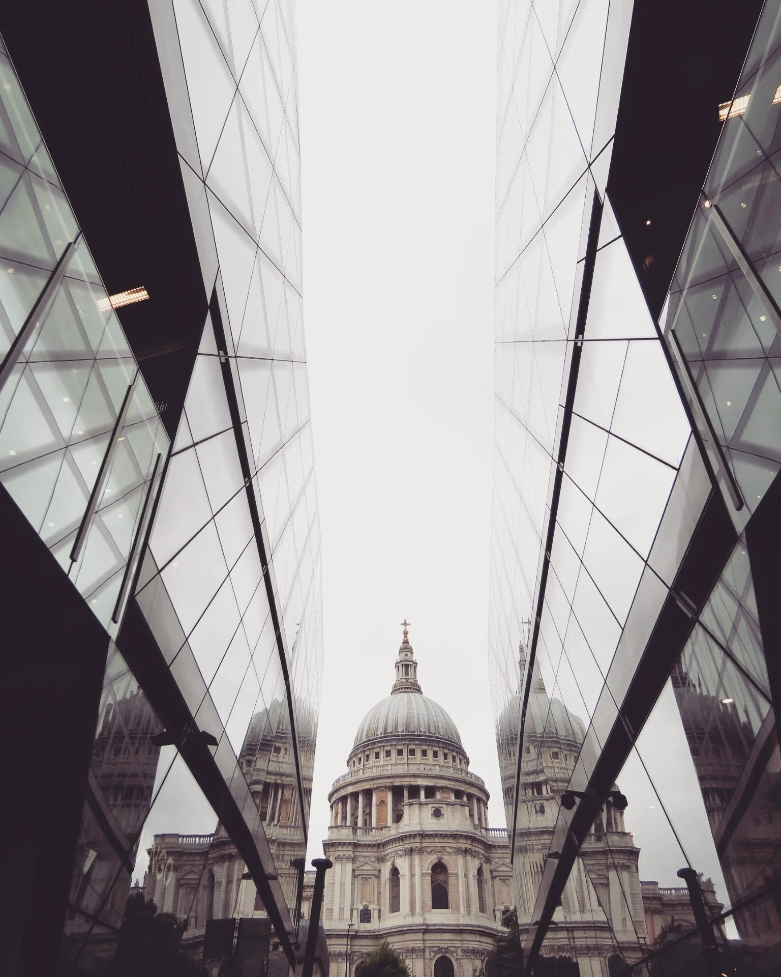 View of St. Paul's Cathedral in London framed by modern glass buildings.