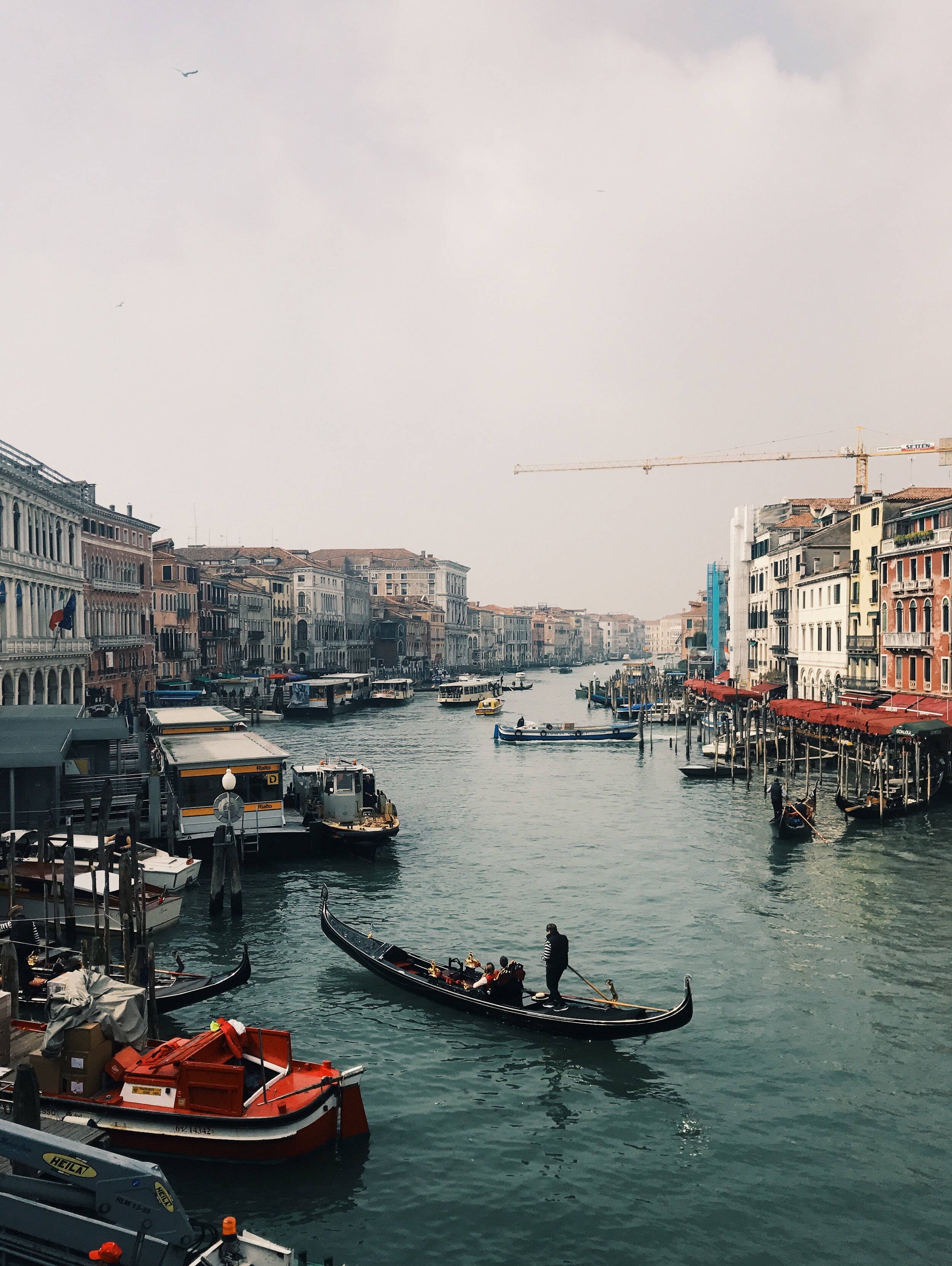 Venetian canal with gondola, water taxis, and historic buildings along the water.