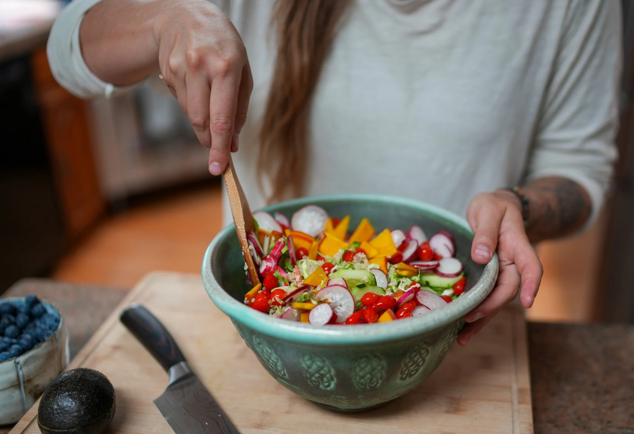 Private Chef in Aspen Colorado Roaring fork valley  stirring a colorful vegetable salad in a green bowl in a kitchen.