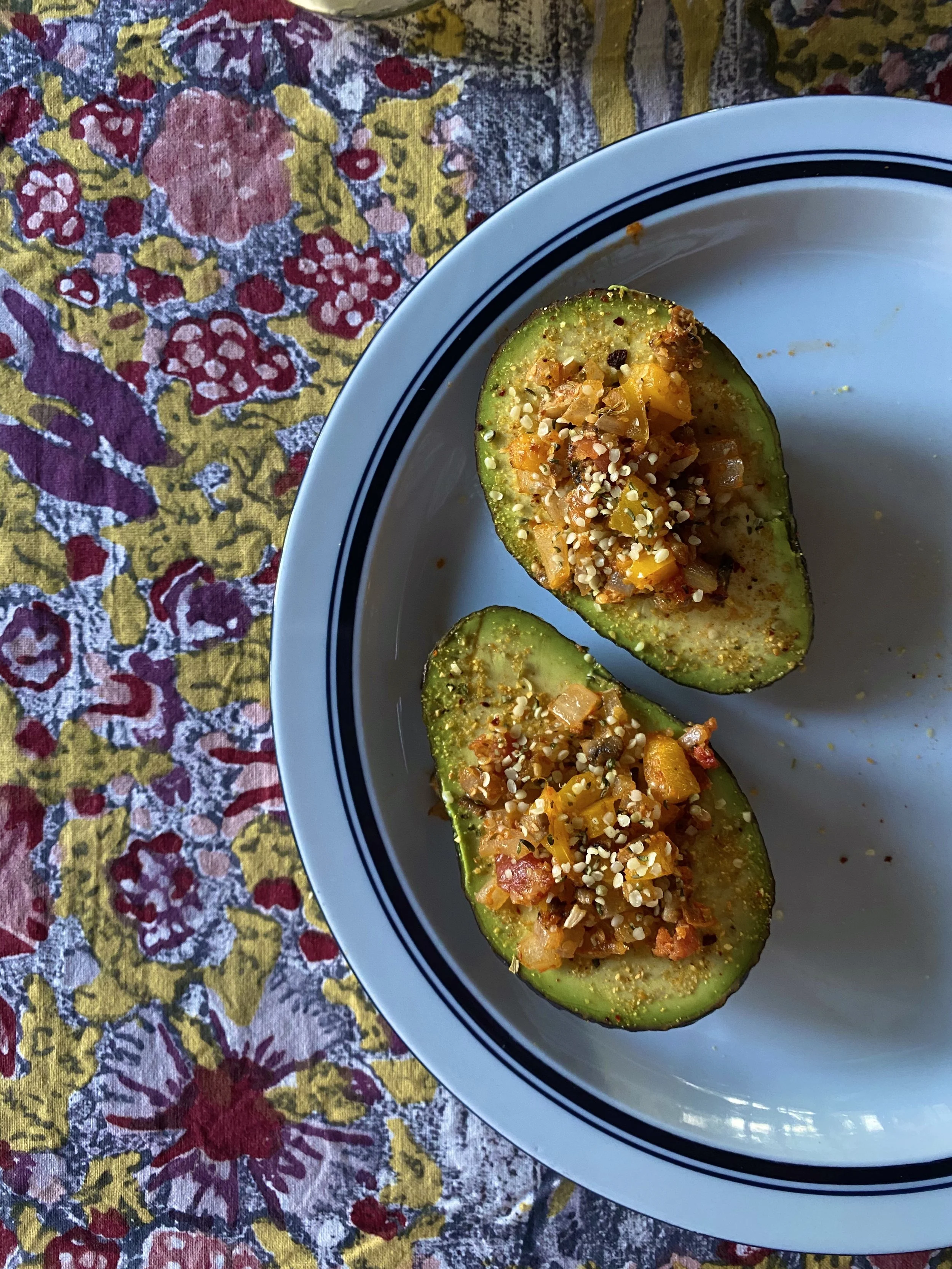 Private Chef in Aspen Colorado Roaring fork valley With Two halved avocados filled with a colorful vegetable mixture topped with seeds and spices, breakfast menu