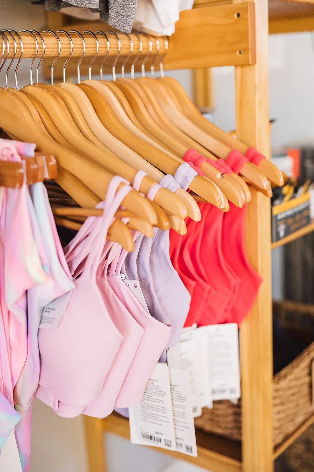 Colorful swimsuits hanging on wooden hangers on a wooden rack, with tags attached, in a store.