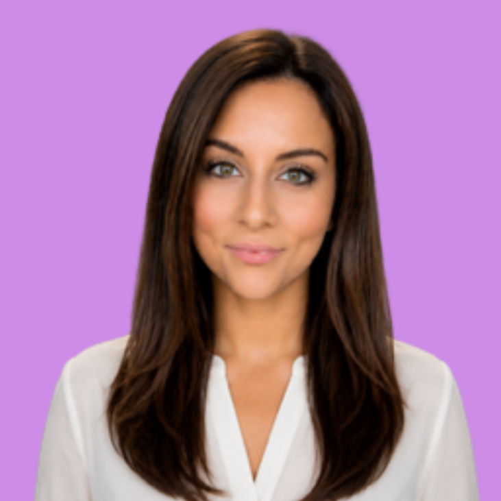 A white woman with long, dark brown hair smiles closed-mouth at the camera. She has green eyes and wears a white blouse.