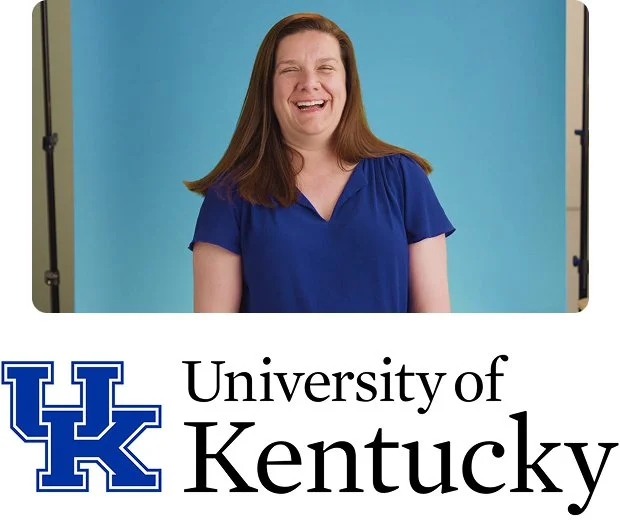 A white woman with medium length brown hair wearing a blue and white collared shirt smiles in front of a blue background above the University of Kentucky name and logo.