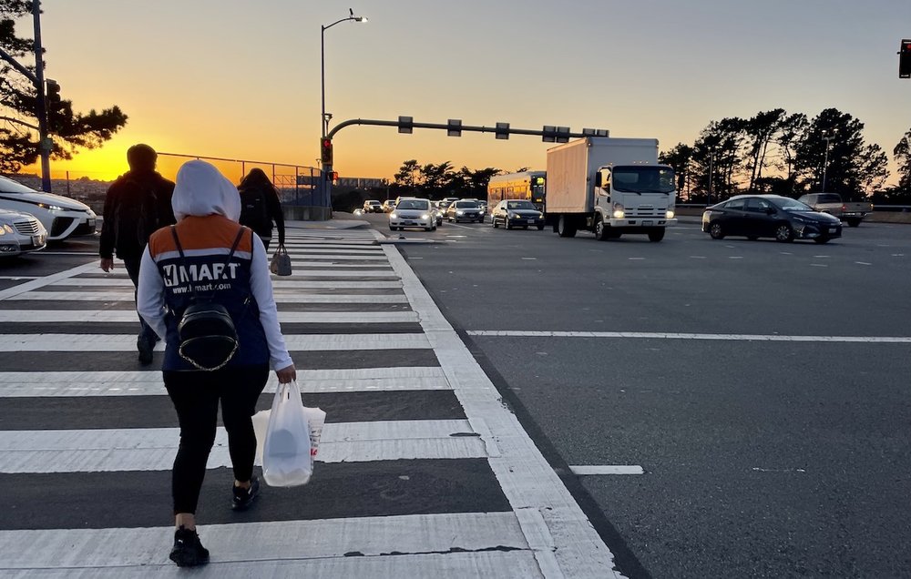 Pedestrians cross at a busy intersection in Daly City, California