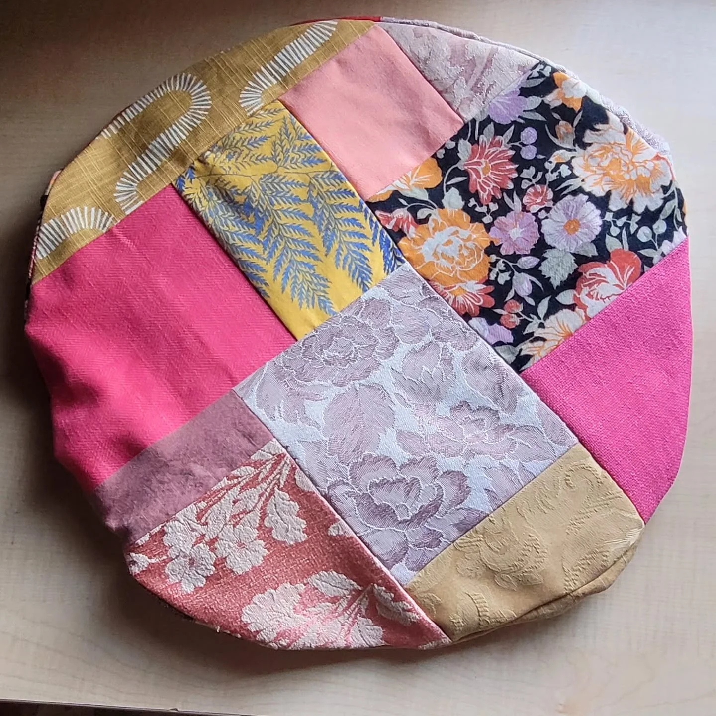 This is an empty patchy pouffe shell. 

It's made from scrap fabric from making other pouffe shells. 

Those pouffe shells were made from second-hand and recirculated fabrics. 

They're intended to be filled with your fashion waste. Anything that's n