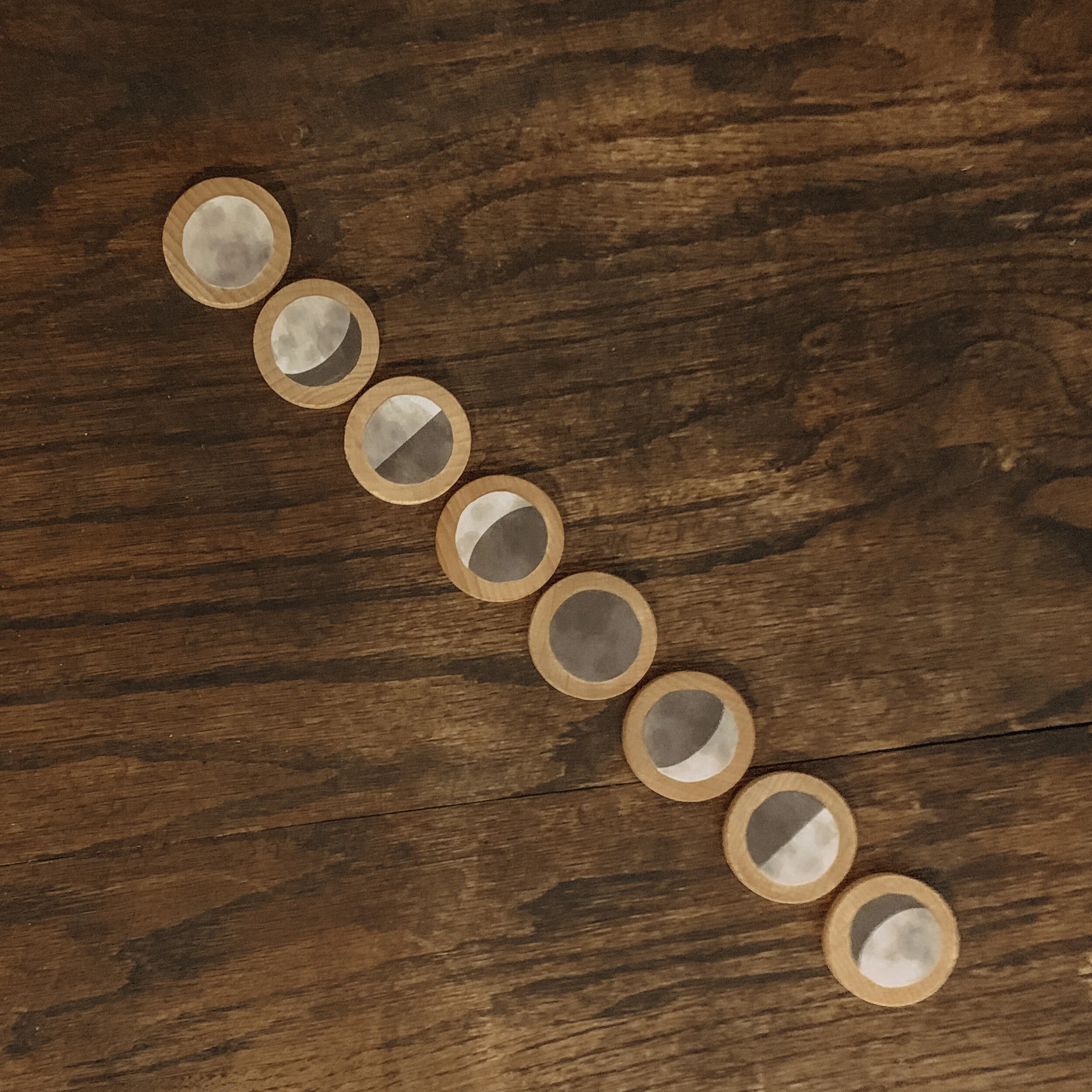 Completed moon phases wooden coins craft Montessori-inspired lunar learning activity