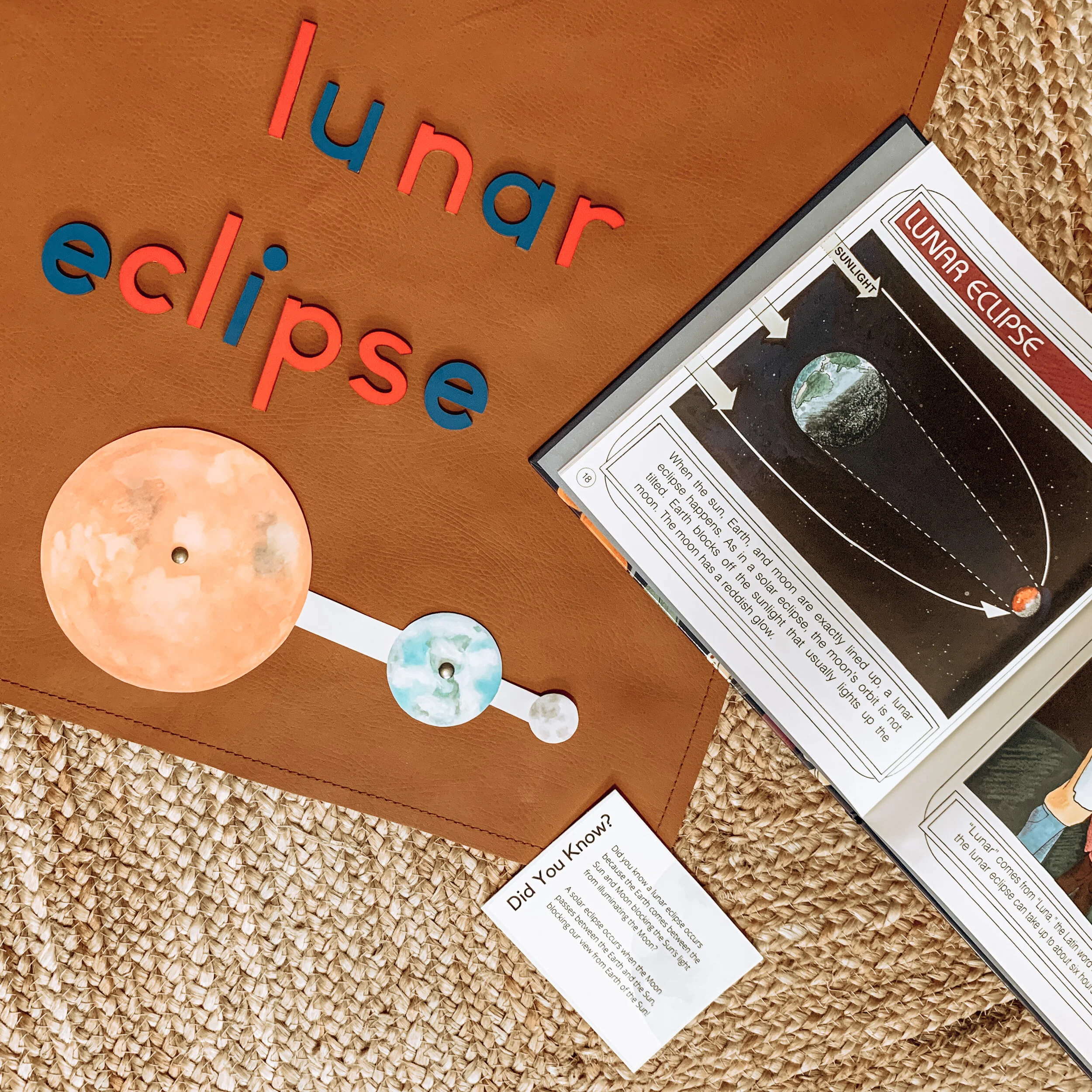 Child completing hand-painted watercolor orbits of Earth and Moon Montessori printable activity by Liza Dora Books