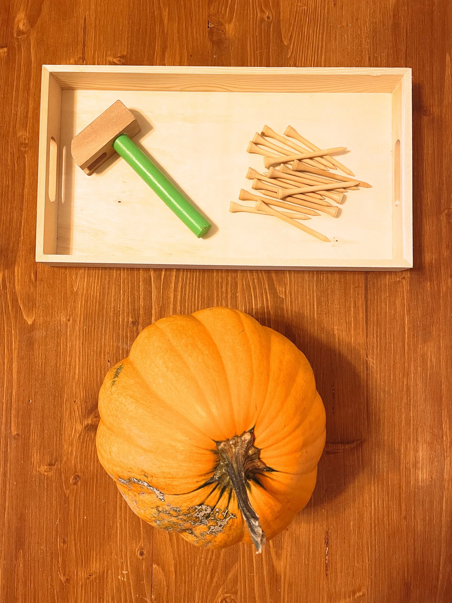 Child doing pumpkin hammering activity Montessori-inspired fall craft for toddlers and preschoolers