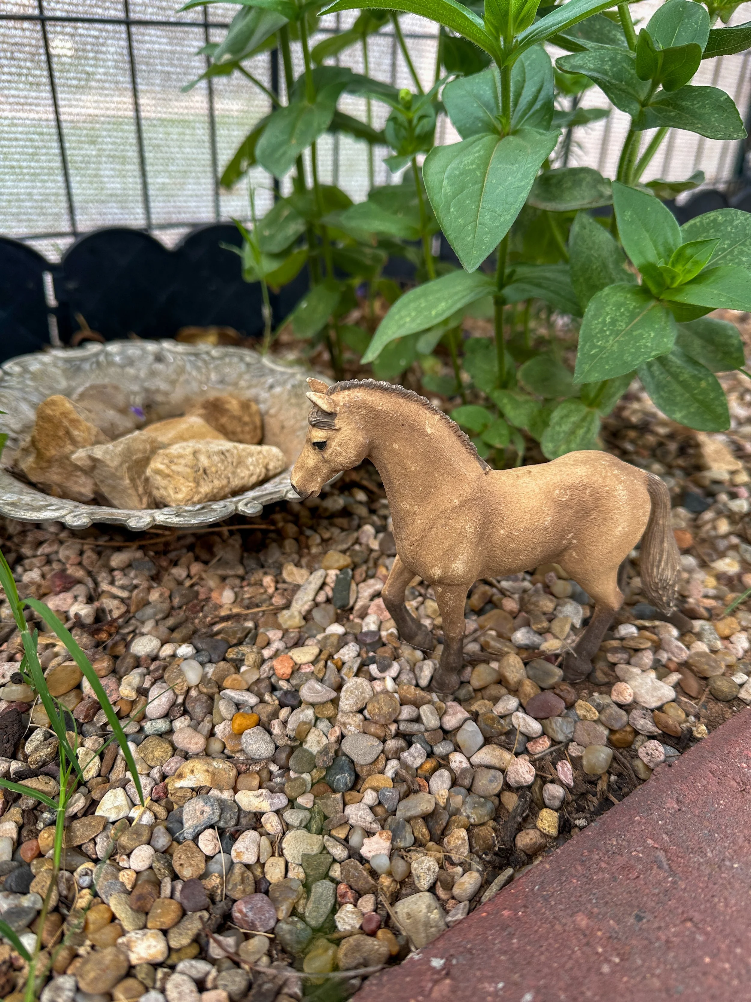 Toy animal in a backyard garden, taking inside toys outside for screen-free summer pretend play