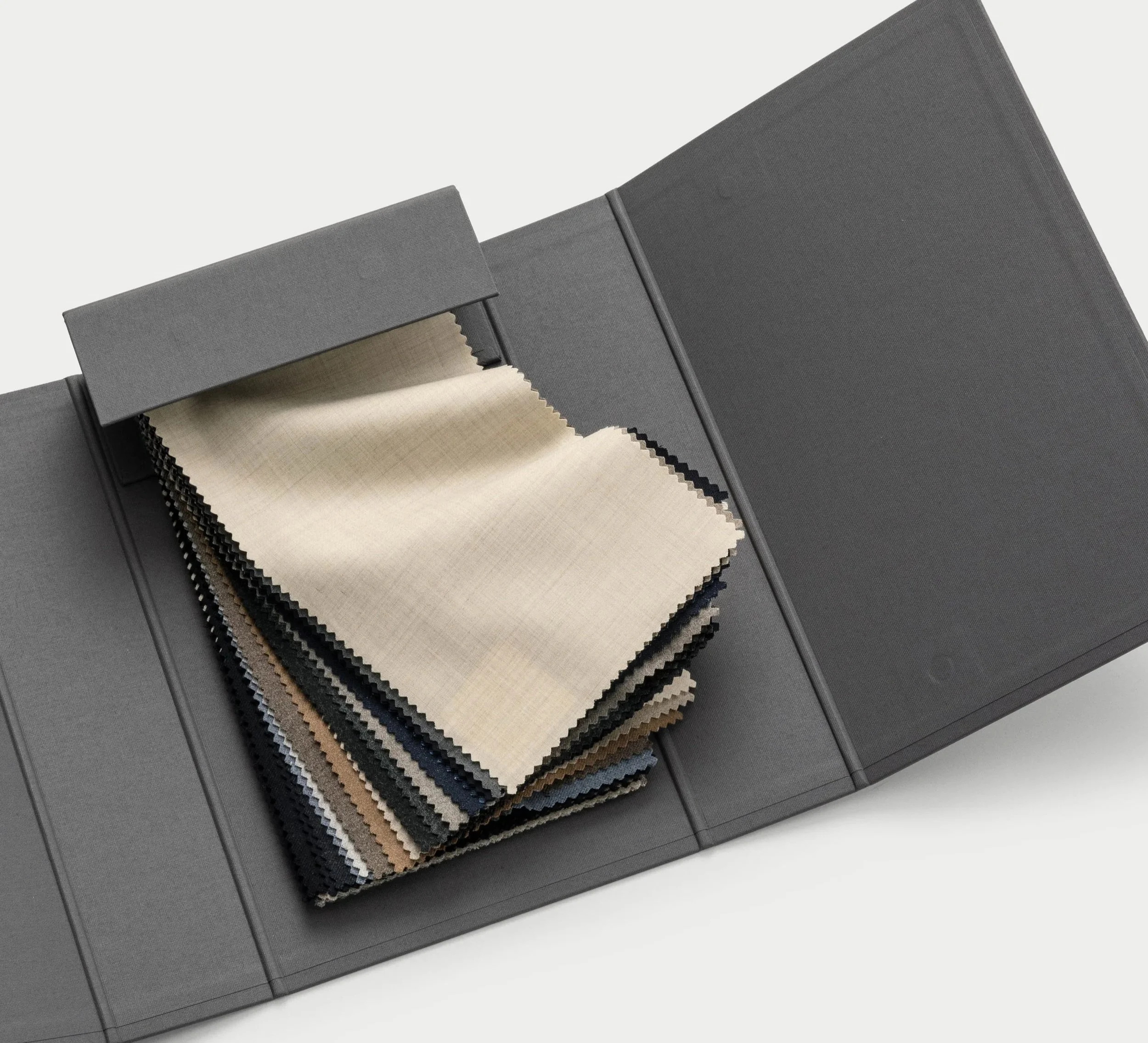 A gray fabric sample book with a pull-out tab showing fabric swatches in beige, brown, and black colors.