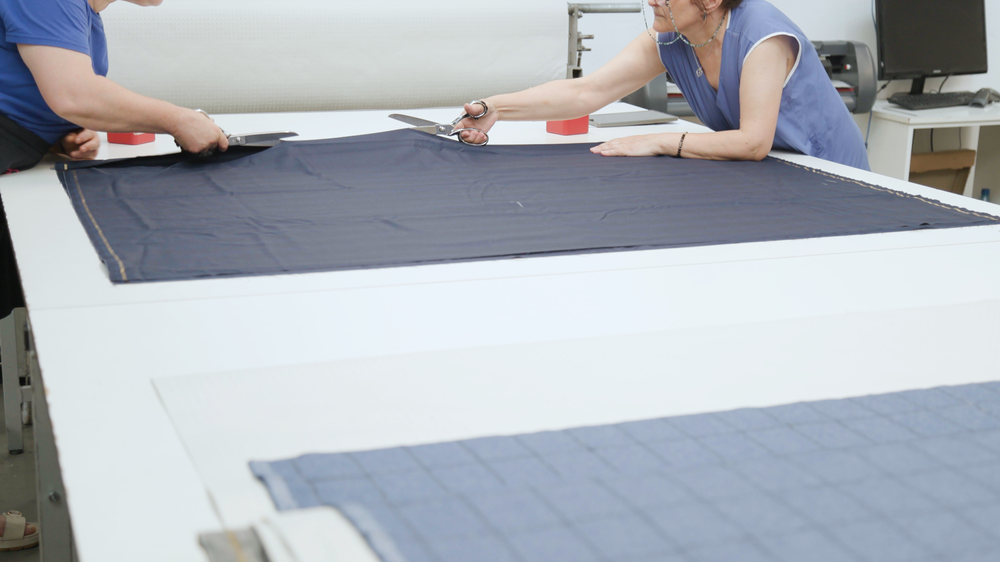 Tailor cutting chalk-marked cloth with shears