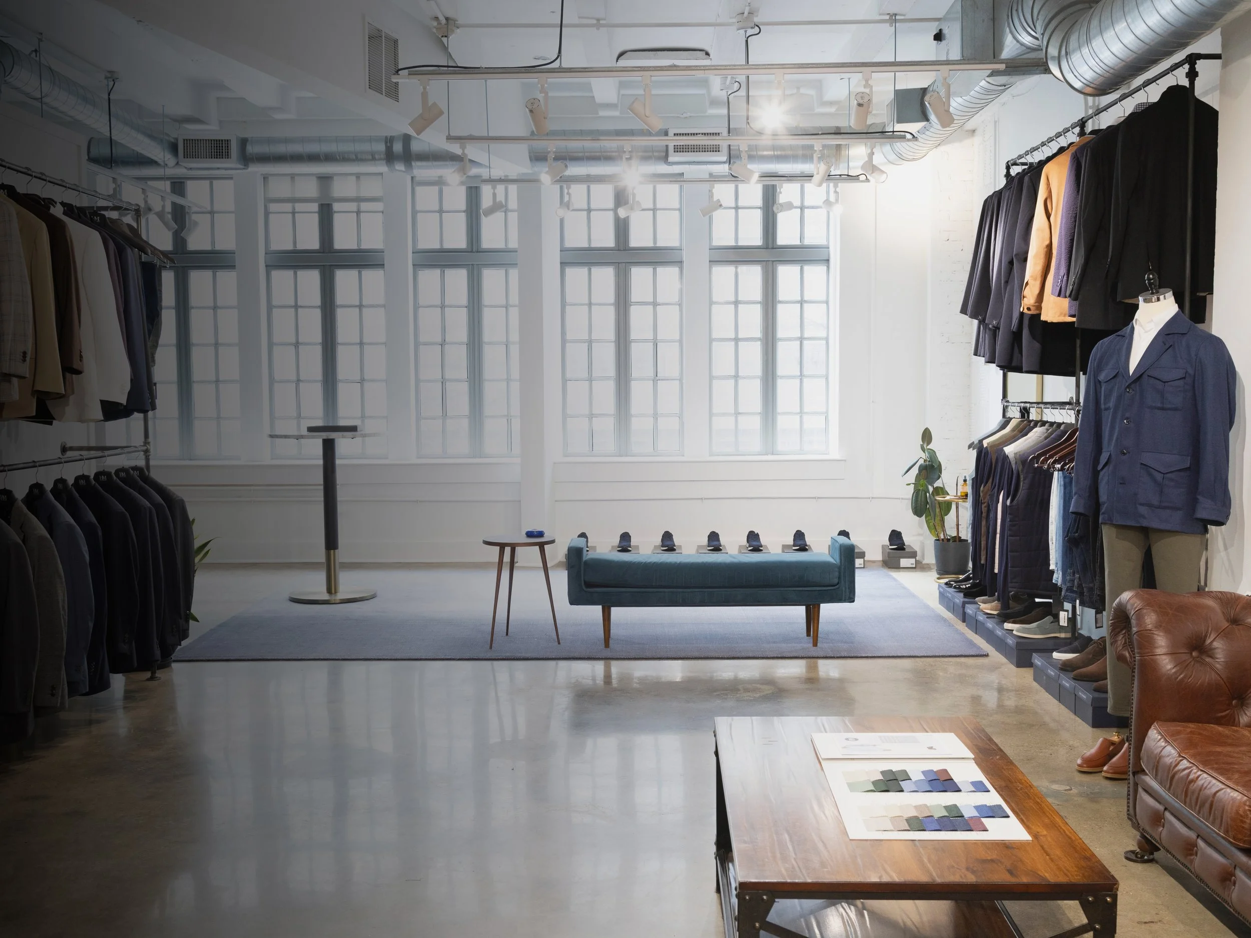 Hall Madden showroom with a marble table, olive branches and a navy suit on a form