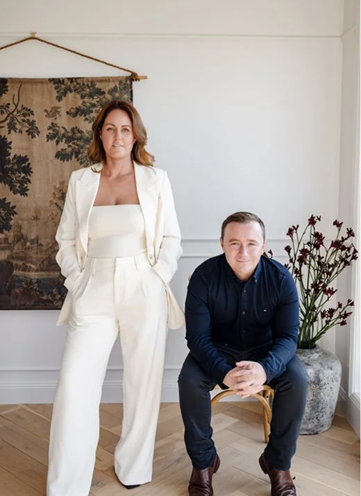 A picture of Will Miller and Rosie Long, co-founders of Sale Street Real Estate, in a beautiful room with chevron floorboards and an antique wall hanging
