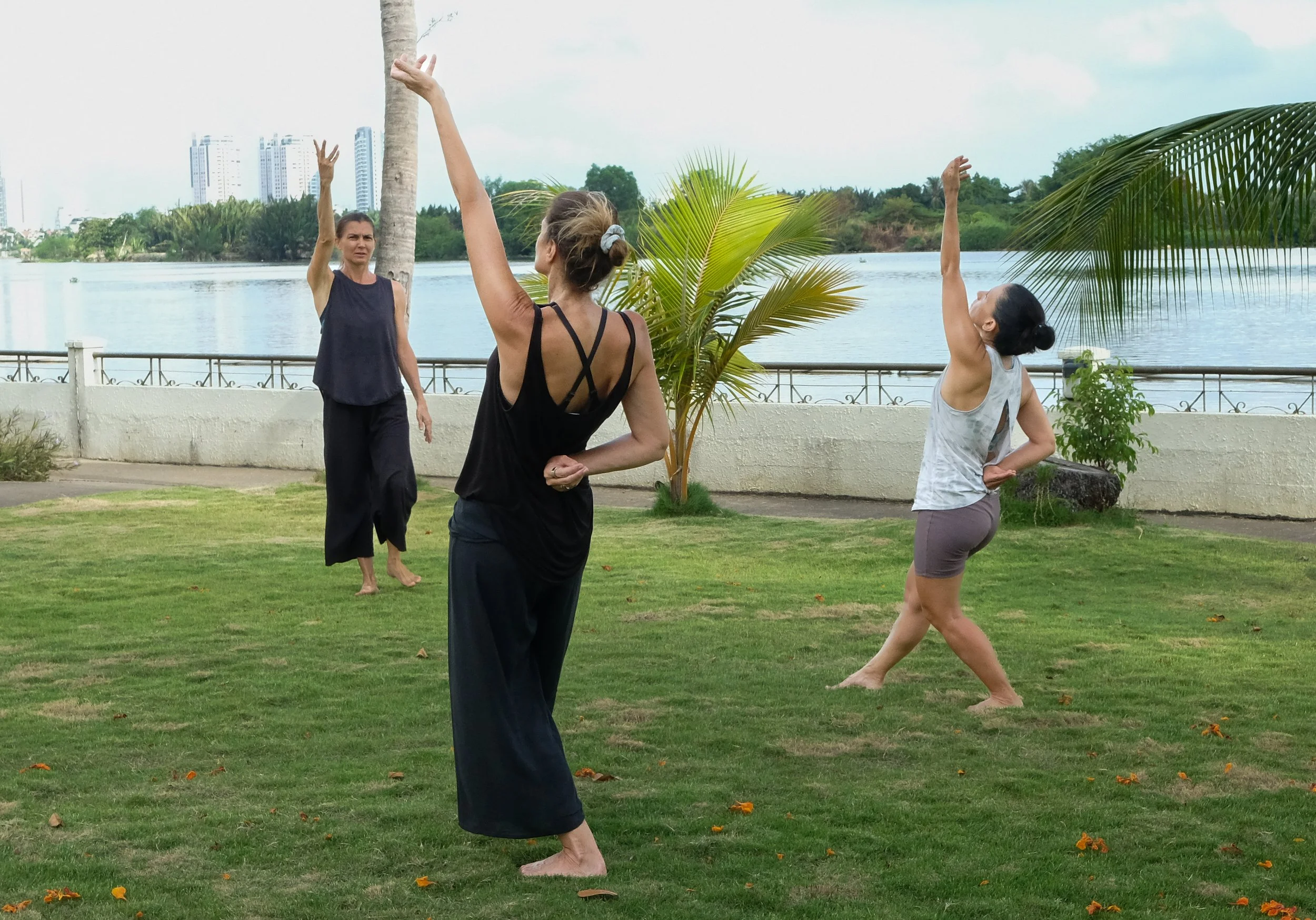 Ani Petrova leading a small Taoist Qi Gong group practice outdoors by the water in Vietnam.