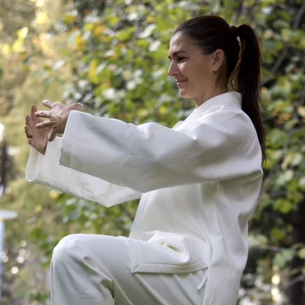 Ani Petrova practicing Taoist Qi Gong in a white training uniform during Wudang-inspired practice in nature.