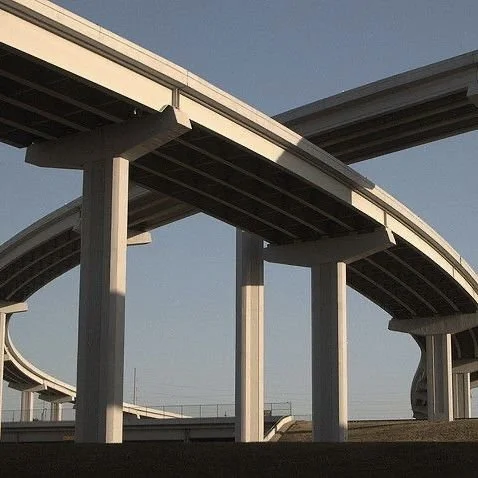 Multiple overpasses and bridges with supporting pillars, under clear blue sky.
