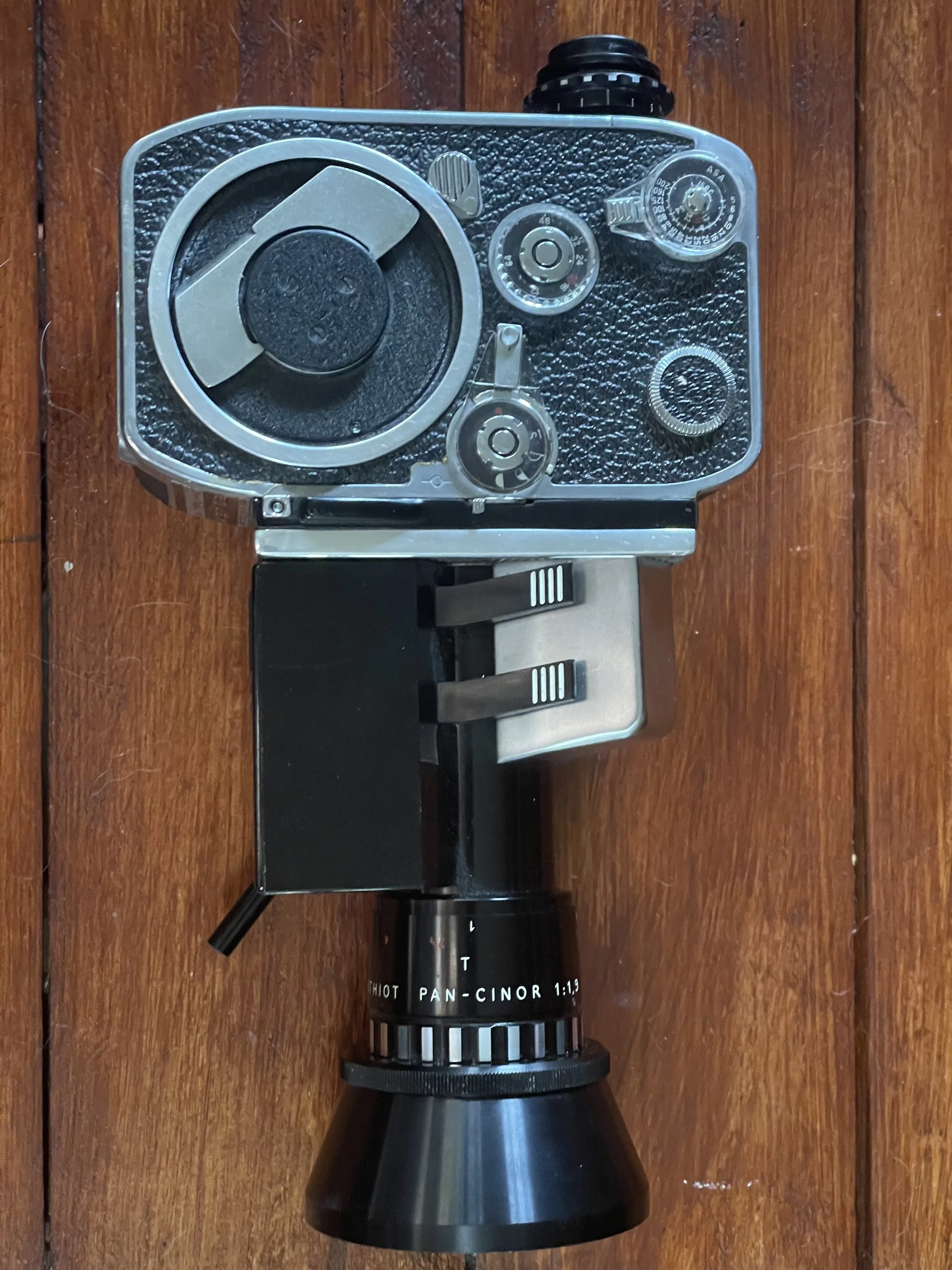 An old film camera with a large lens on a wooden surface.