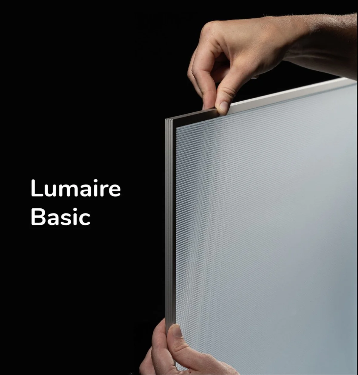 Kuva led paneelin sivusta, jossa käsi asettaa kehyksen paikalleen, teksti "Lumaire Basic" vasemmalla