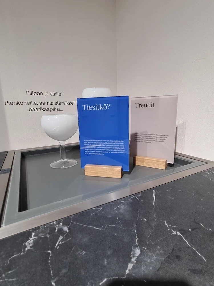 Pöytäkyltit  puisella jalustalla pöydän päällä.