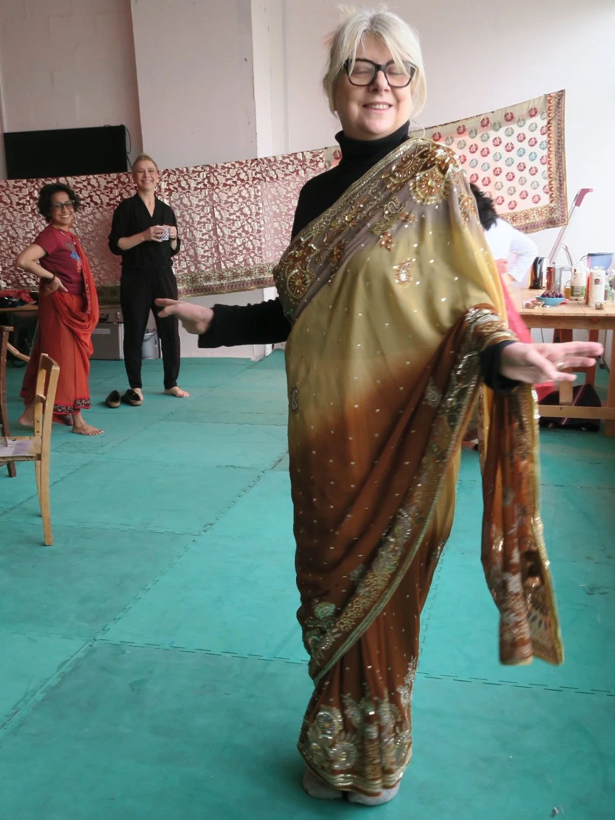 A white-British woman wearing a green saree smiles at the camera