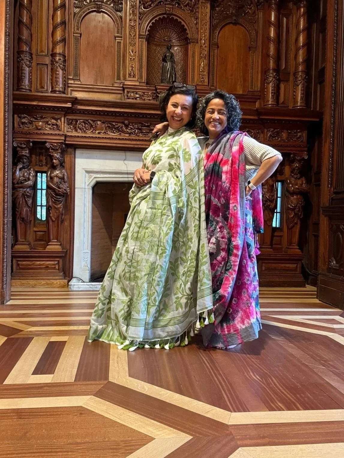 Two British-Bangladeshi women draped in colourful sarees pose together