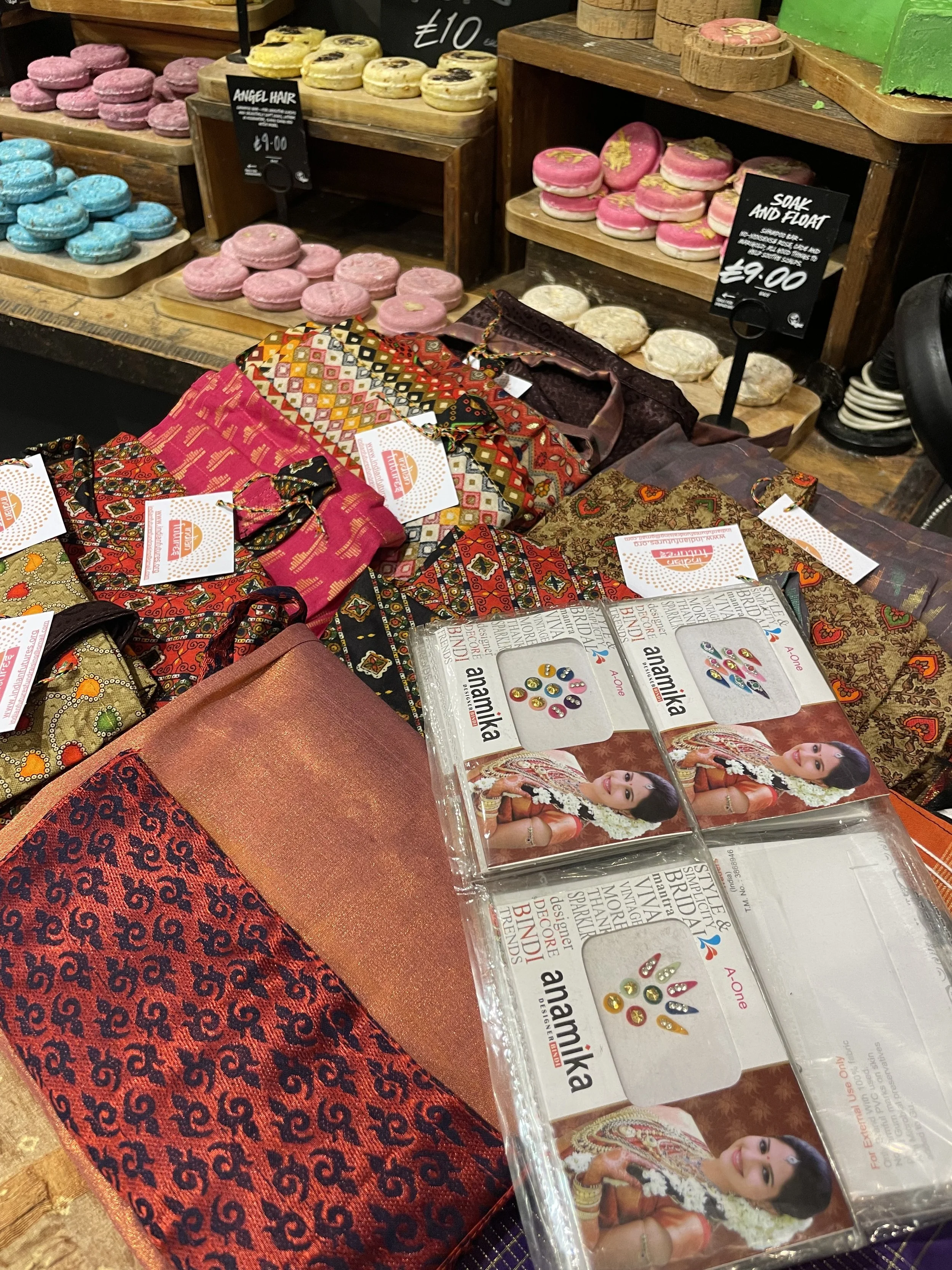 A table with colourful sarees and bath bombs and facial accessories