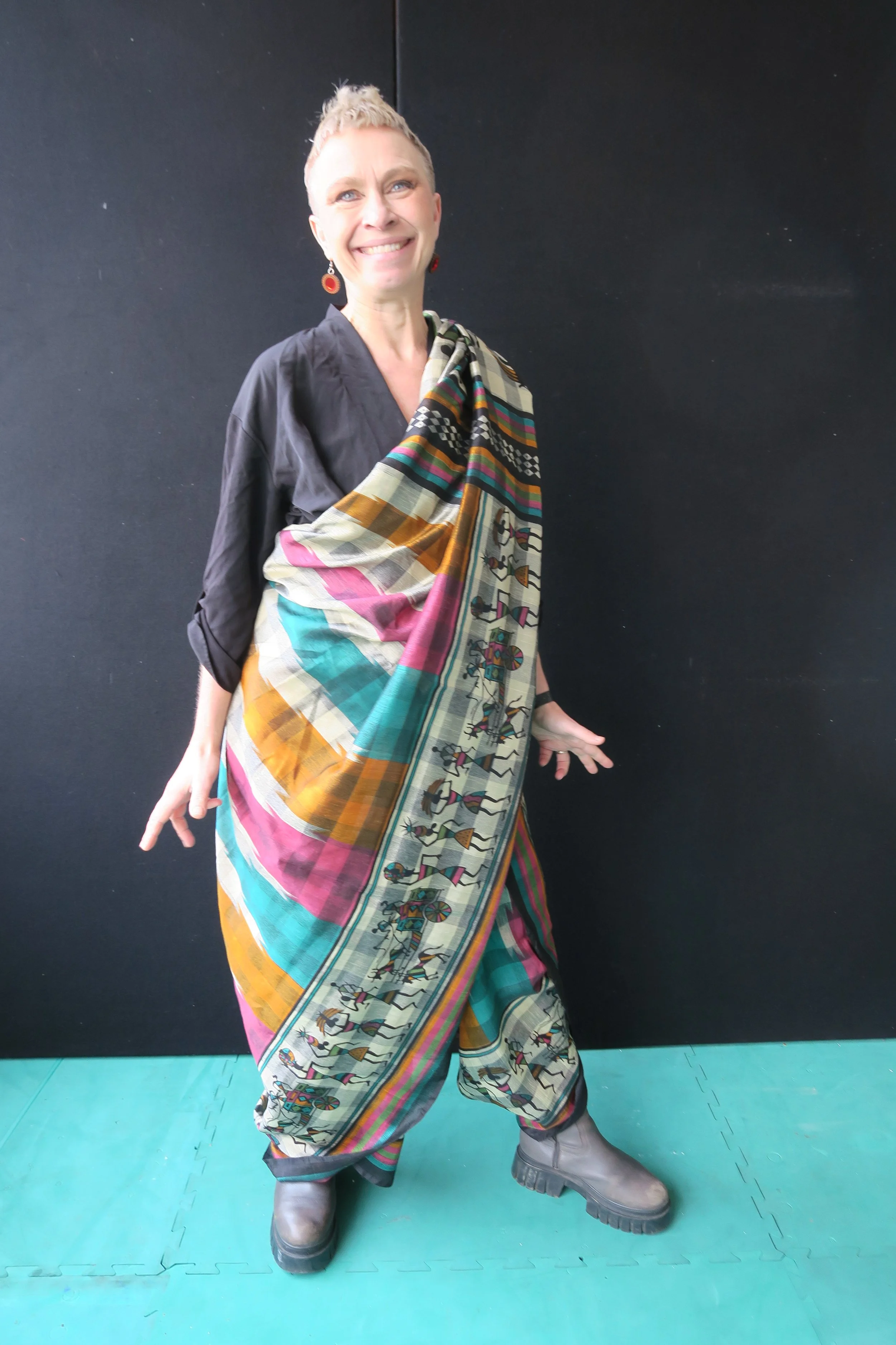 A white British woman wearing a colourful saree in a trouser drape, smiling at the camera