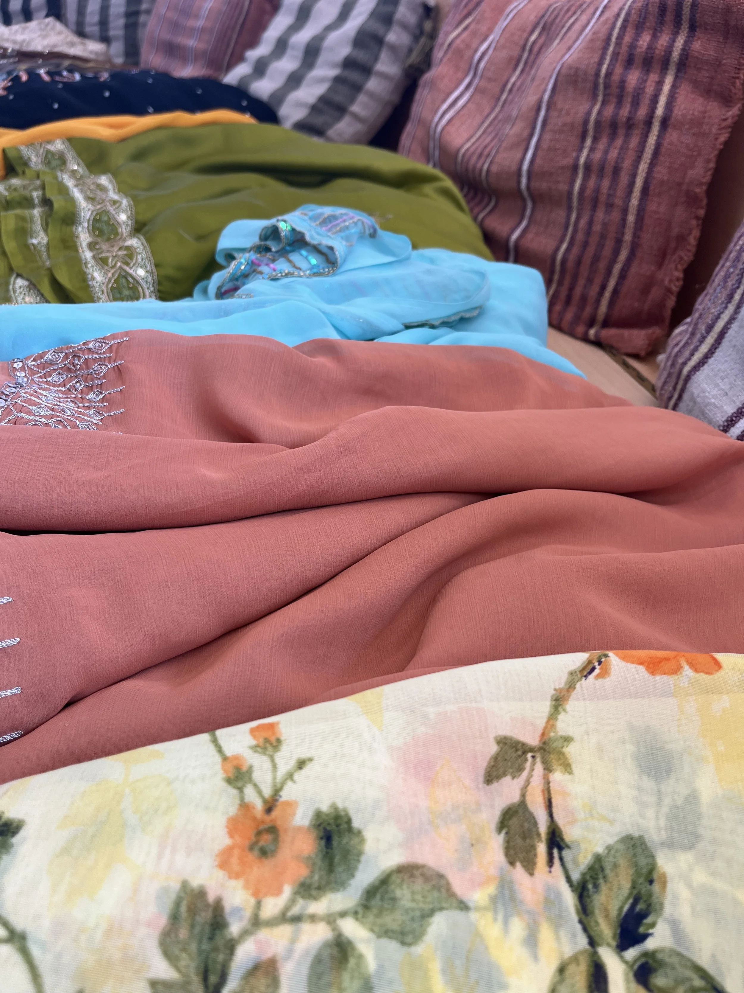 A selection of differently coloured sarees arranged on a table