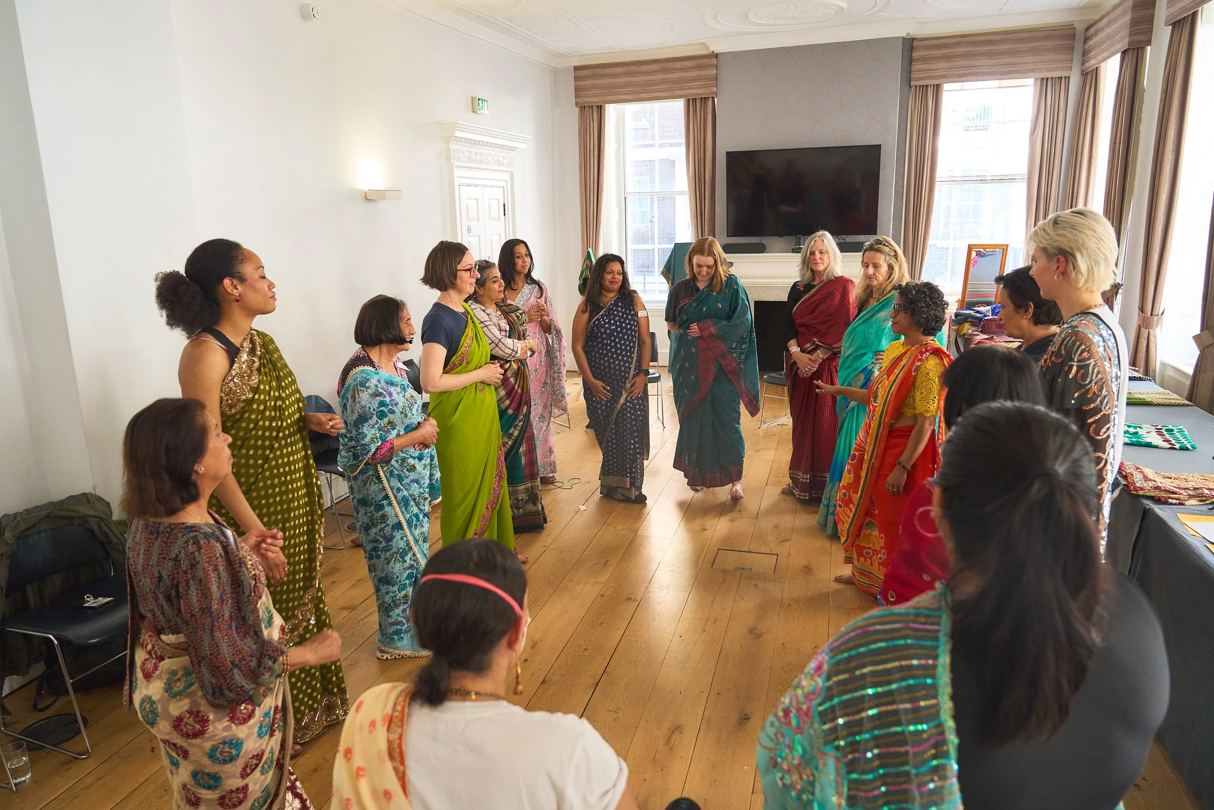 a group of women wearing sarees stand in a circle