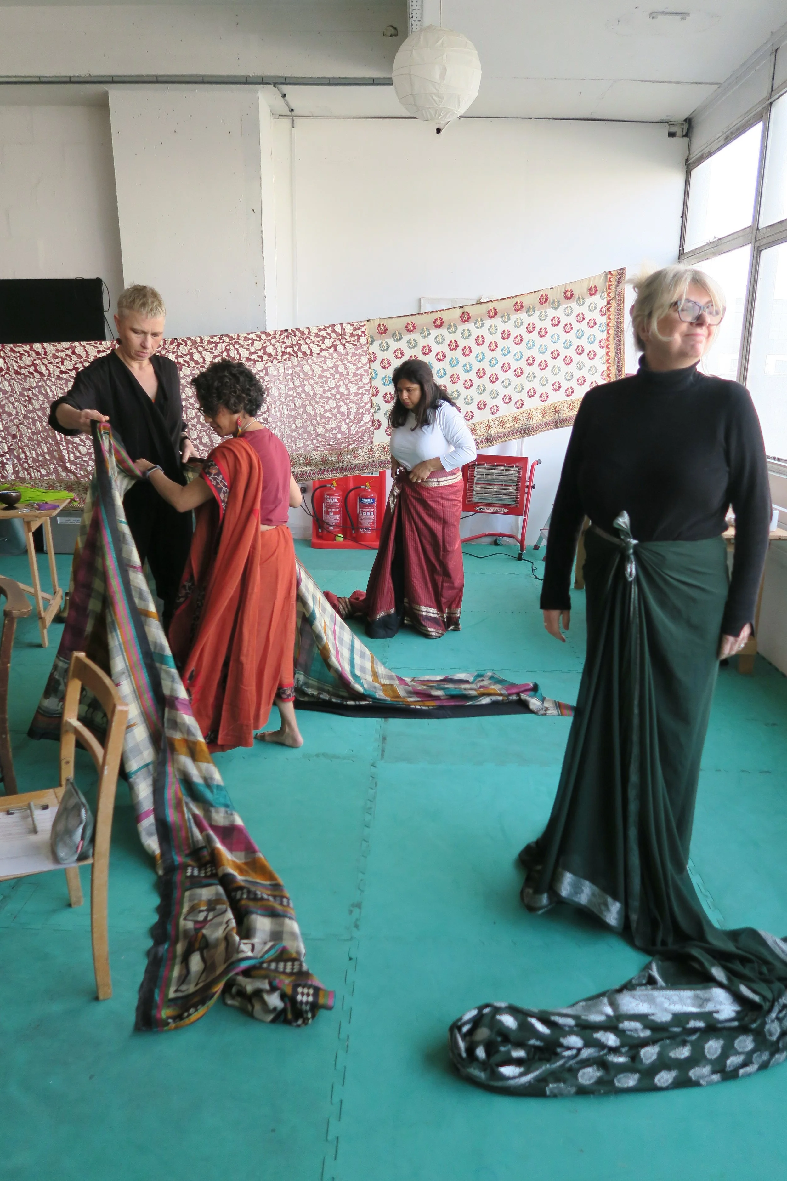 Four women dressing in sarees looking away from the camera