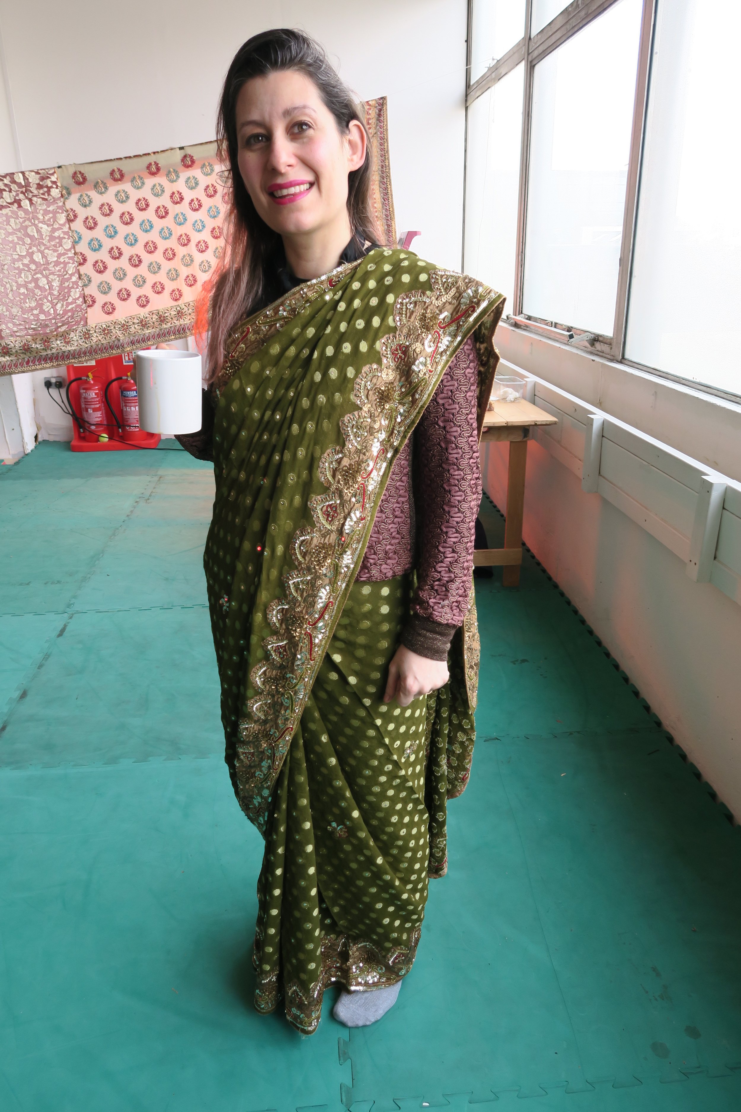 A white-British woman wearing a green saree smiles at the camera