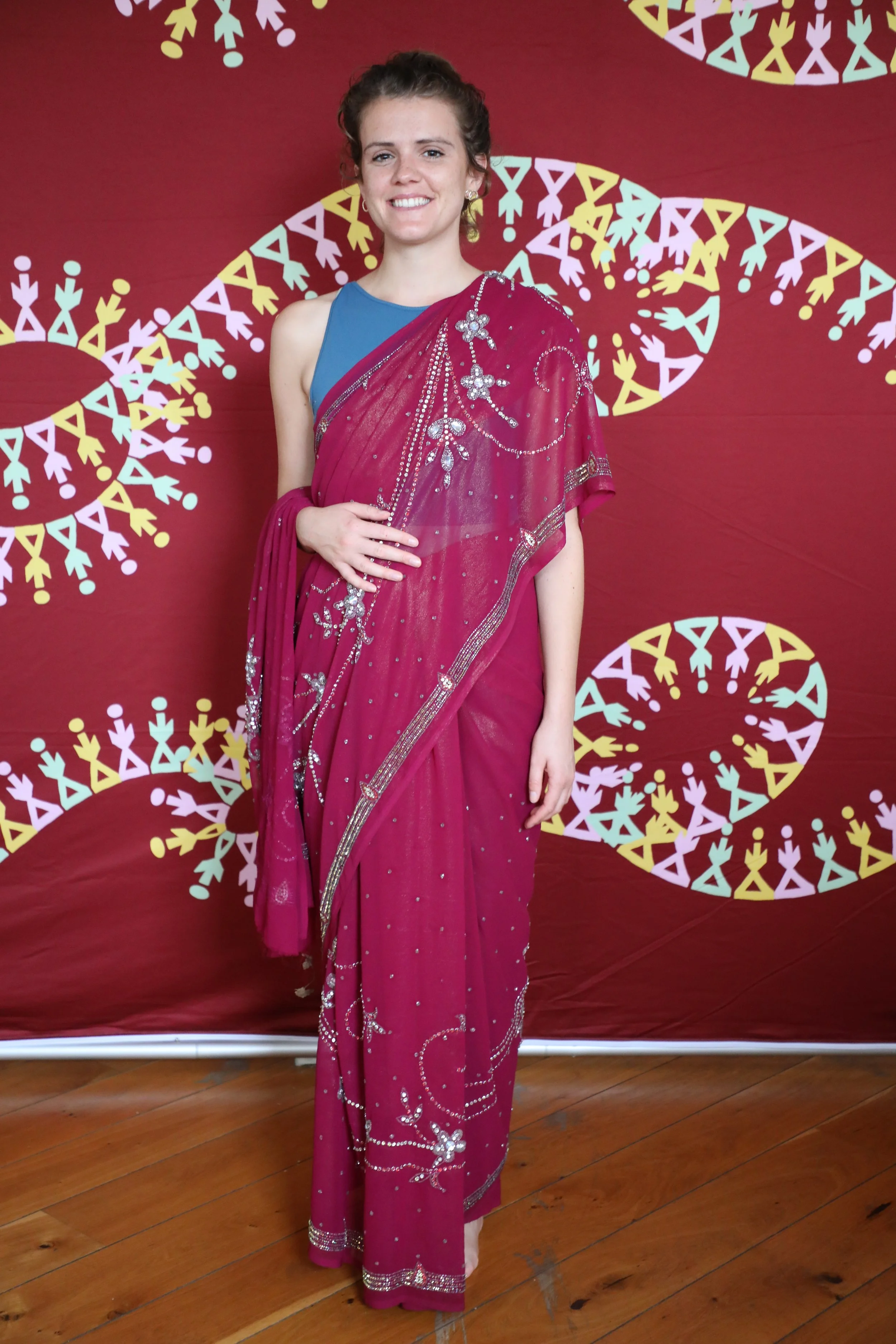 A white British woman wearing a purple saree smiles at the camera
