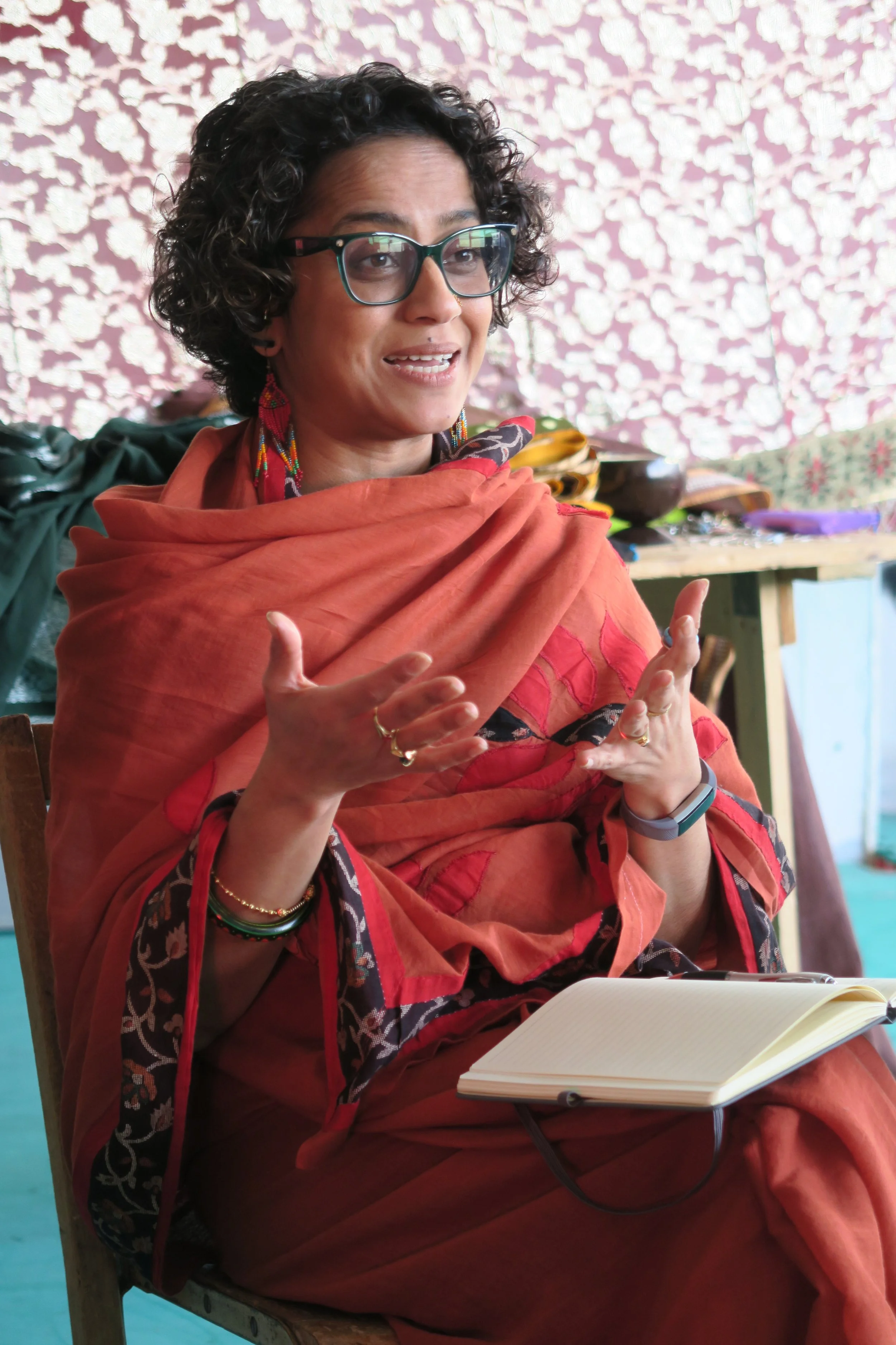 Poppy, a British-Bangladeshi woman, sitting on a chair and talking