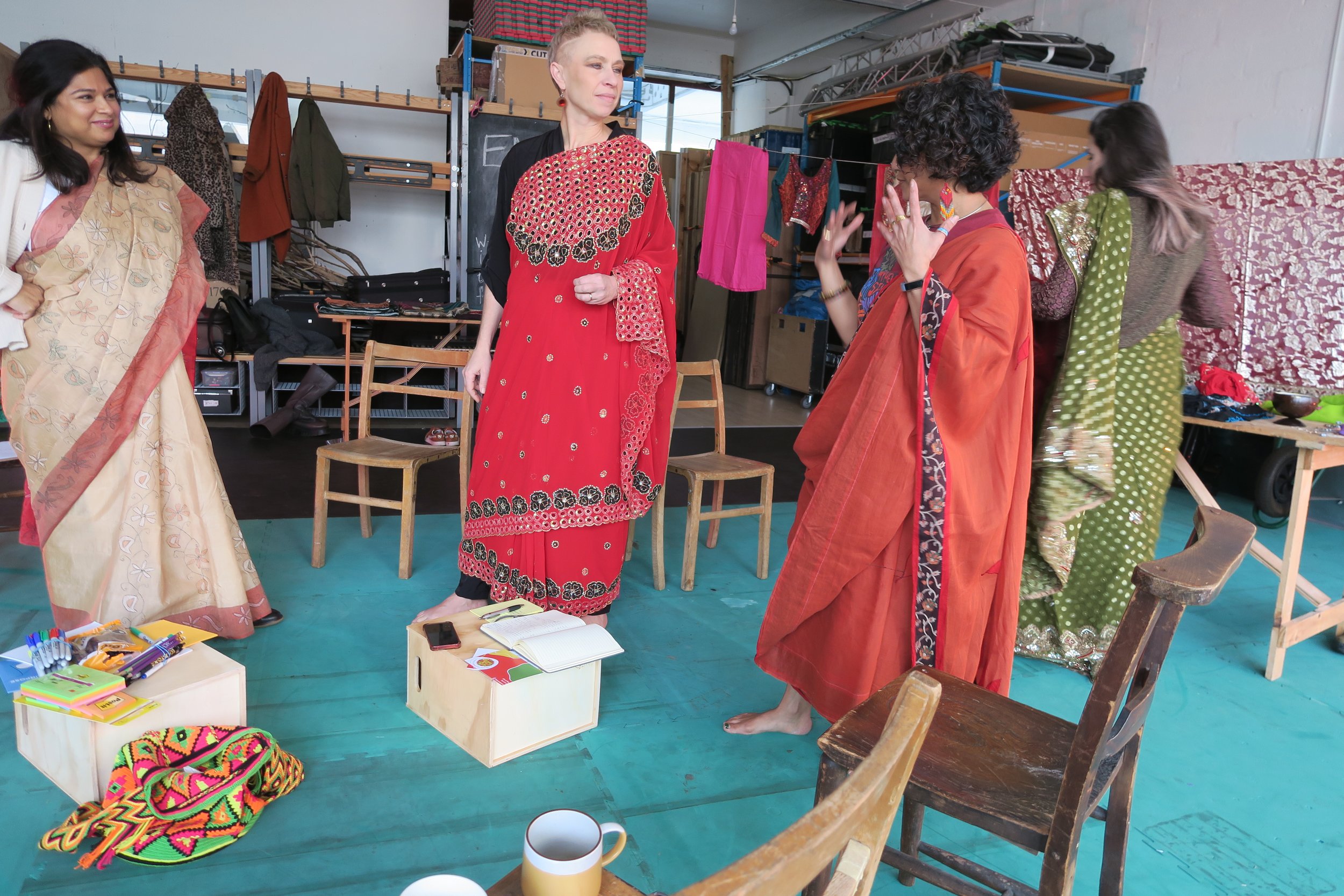 Four women wearing sarees talking to each other and smiling