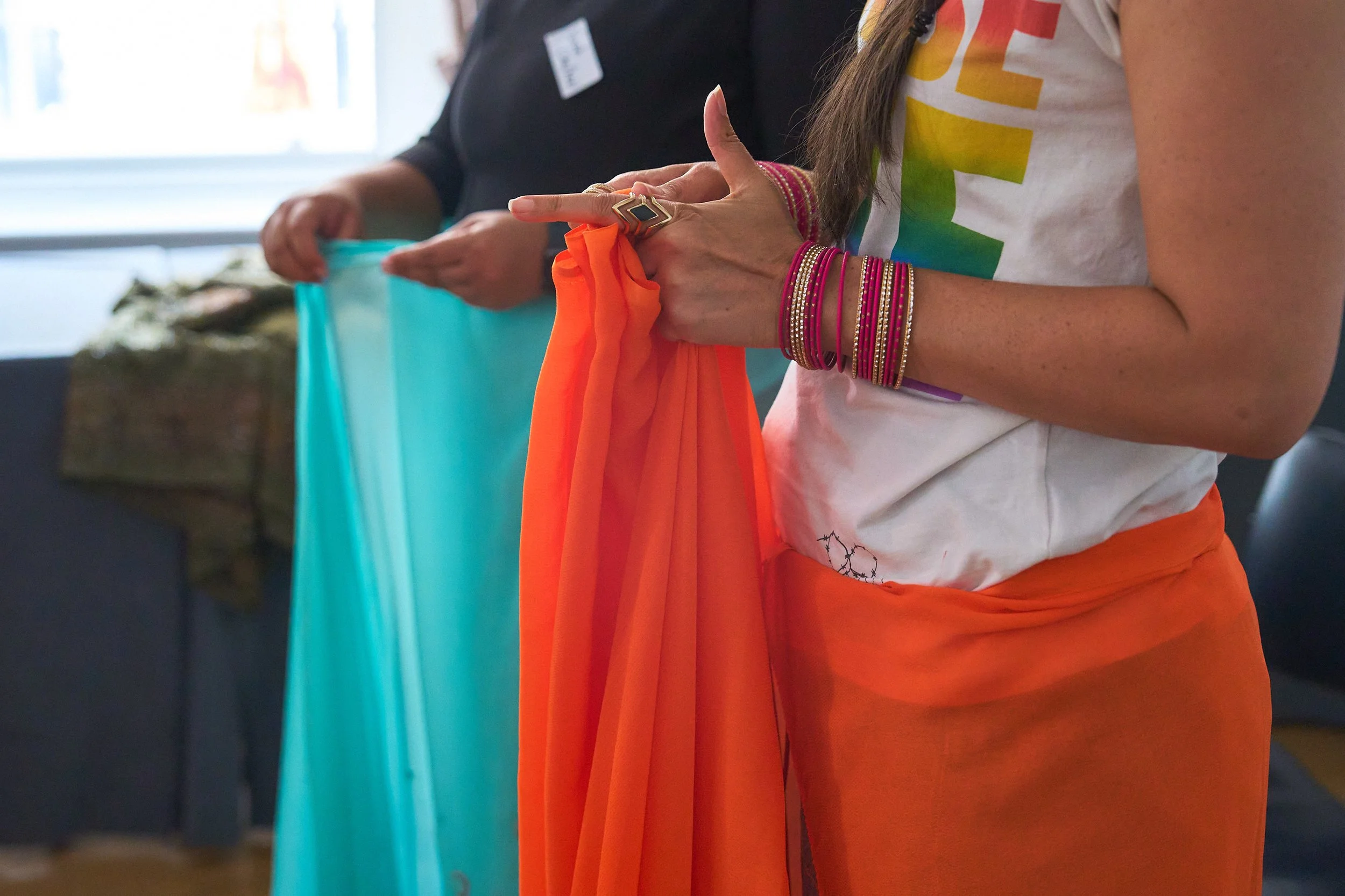 Two women tie a knot in their sarees. This is shot of their mid-frame