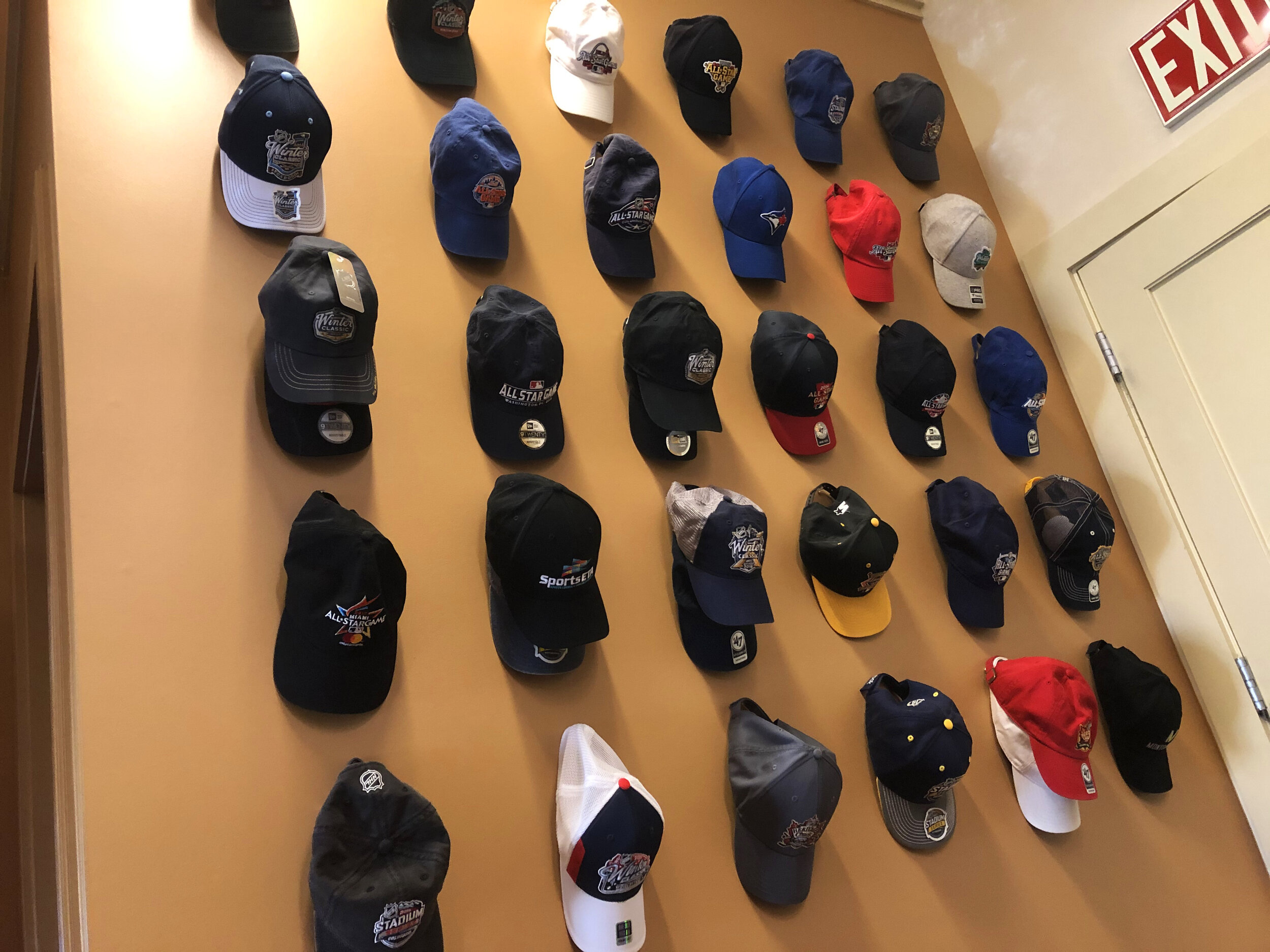 A wall adorned with baseball hats, each with a different sports brand identity.
